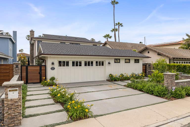  Front of house featuring concrete walkway and driveway with lush, well maintained landscaping.  