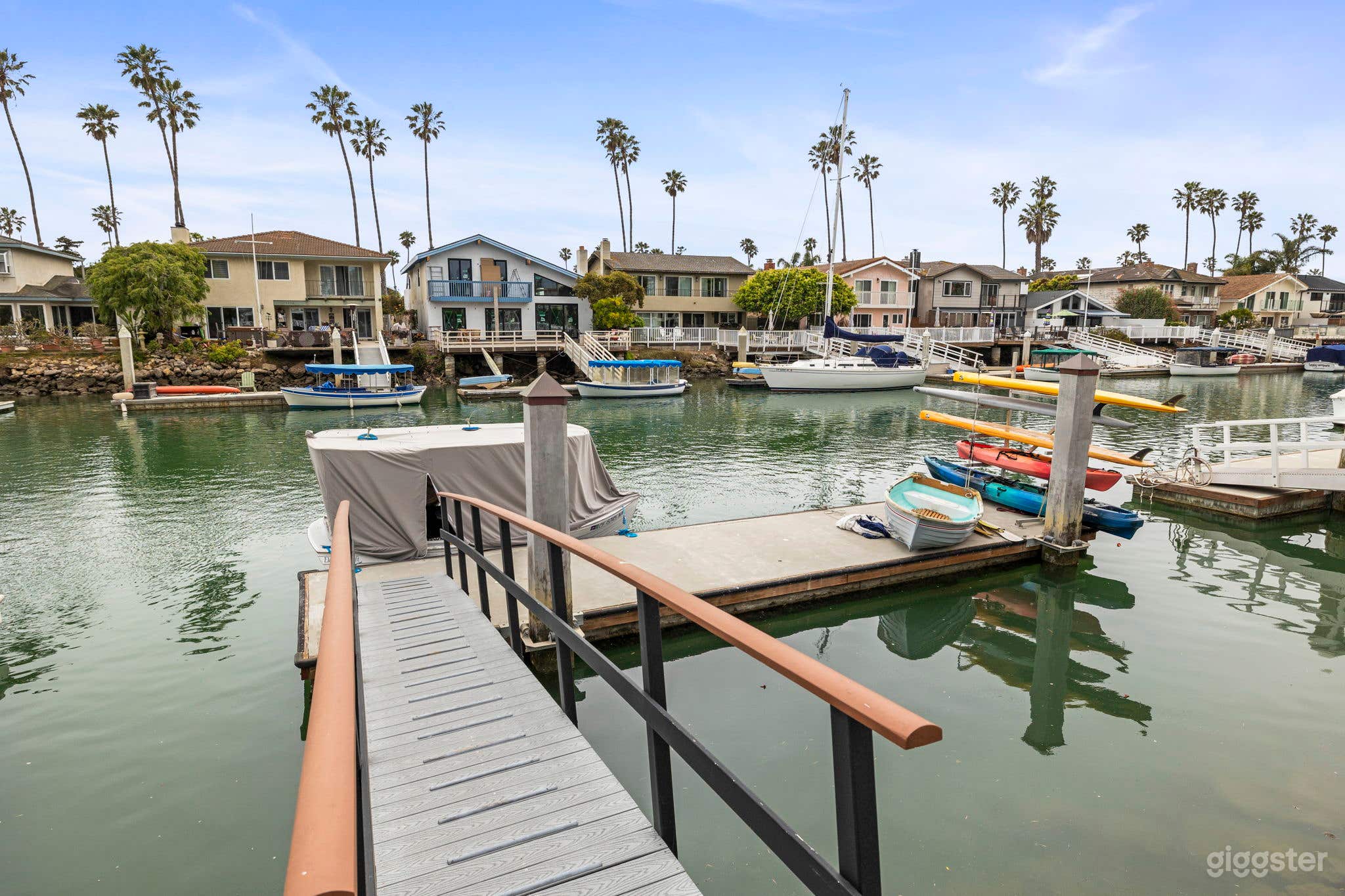 Ramp to private boat dock in the Ventura Keys featuring kayaks, paddle boards, a row boat, and a small dingy. 