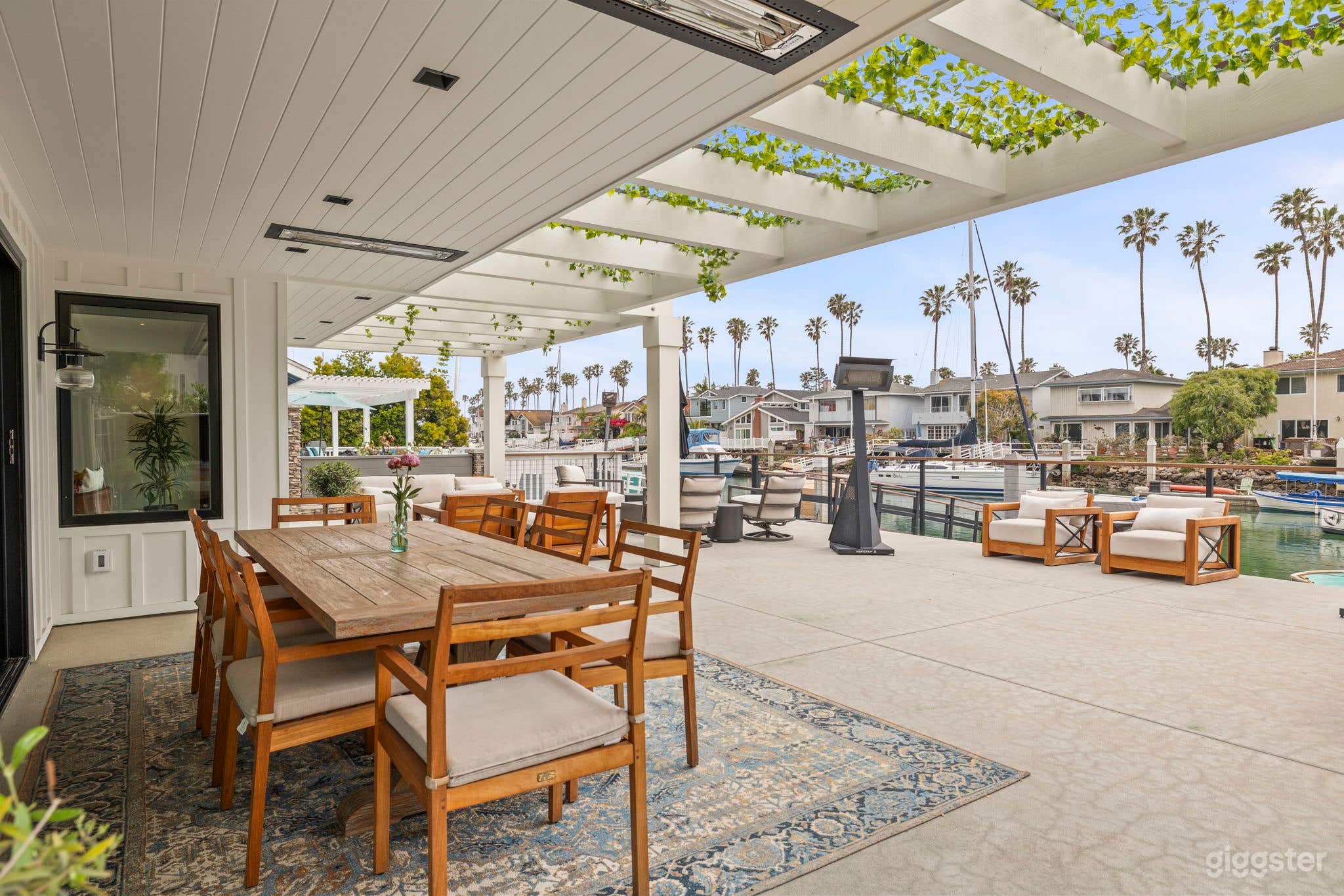 Heated, covered outdoor dining area, lounge chairs, and fire pit on concrete deck.