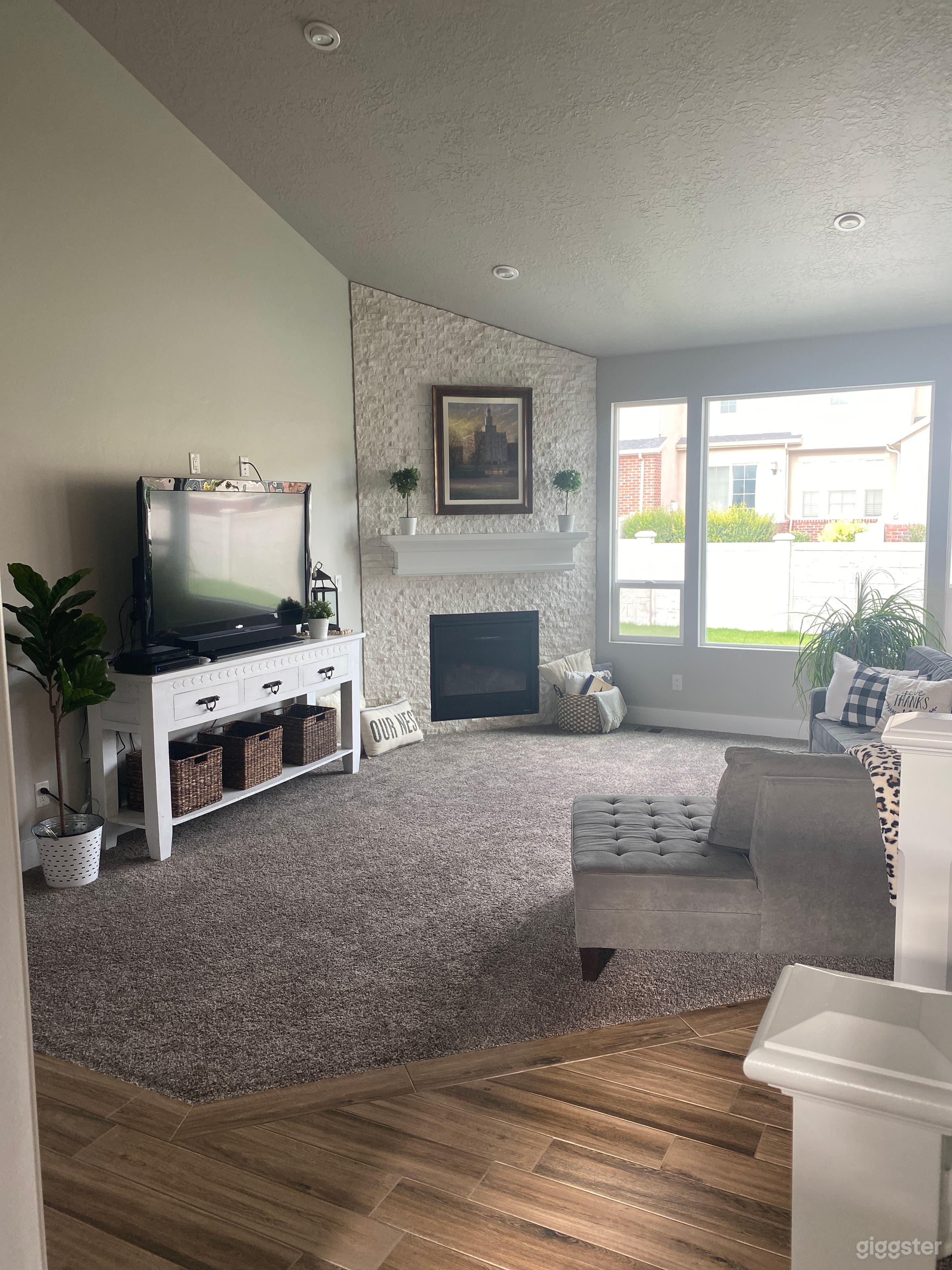 Family room with gray wrap around couch and white fireplace