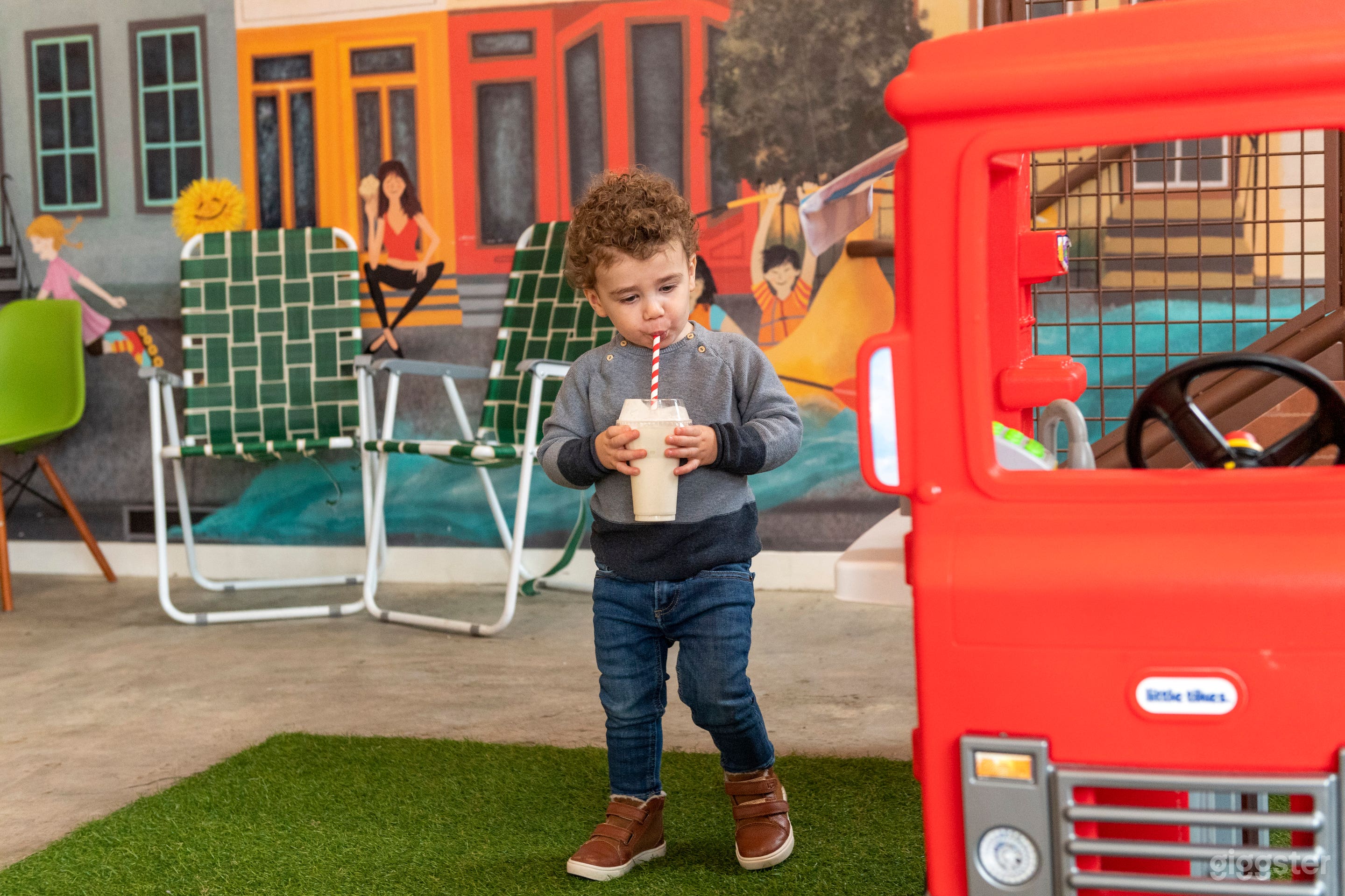 child in front of mural and playspace