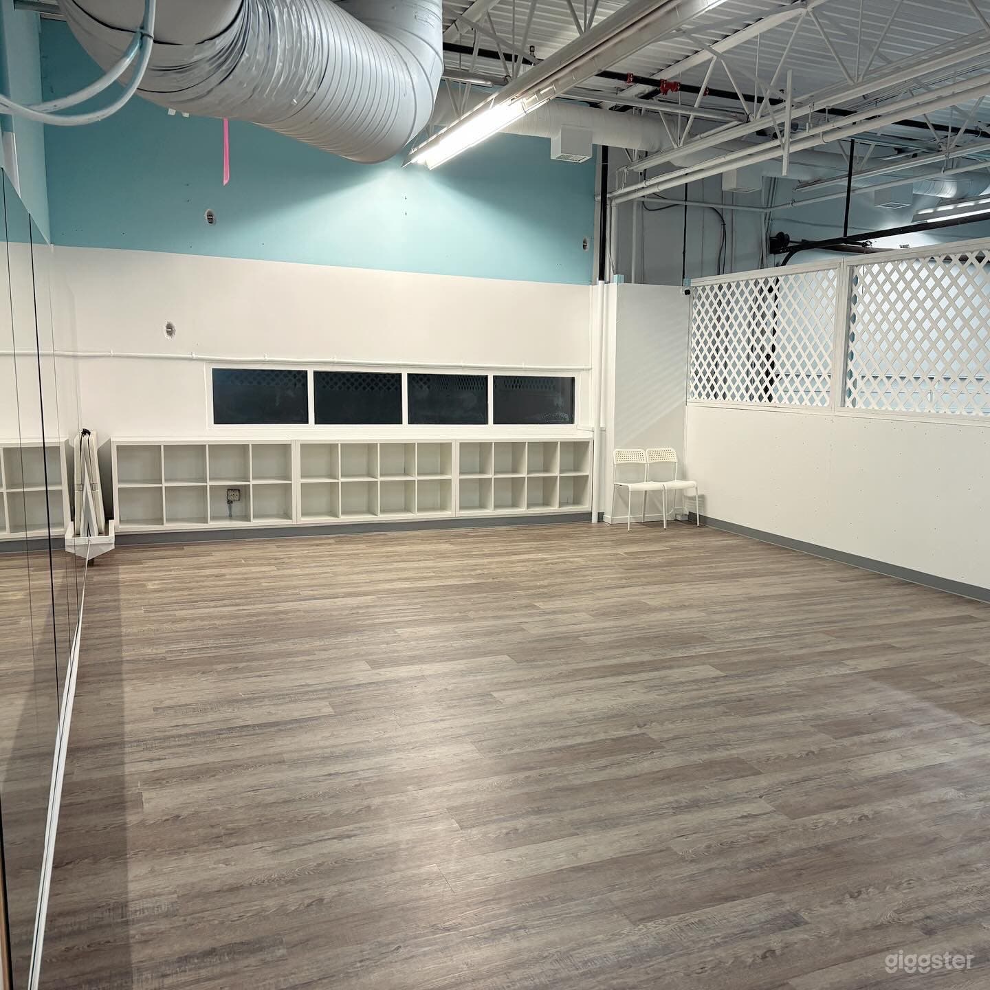 600 sq. ft. mezzanine studio/flex space. vinyl plank flooring, white walls, mirrors &amp; some skylights/windows.