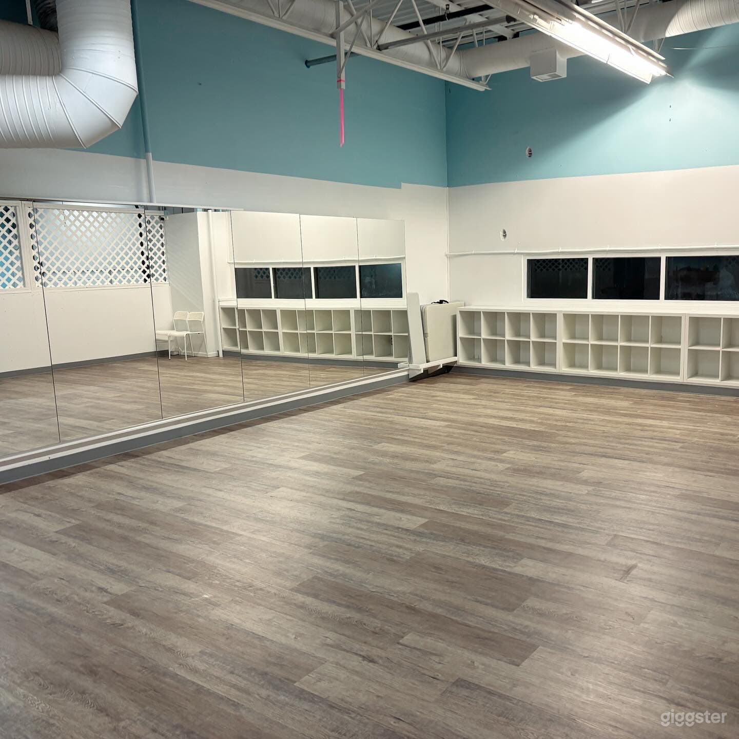 600 sq. ft. mezzanine studio/flex space. vinyl plank flooring, white walls, mirrors &amp; some skylights/windows.