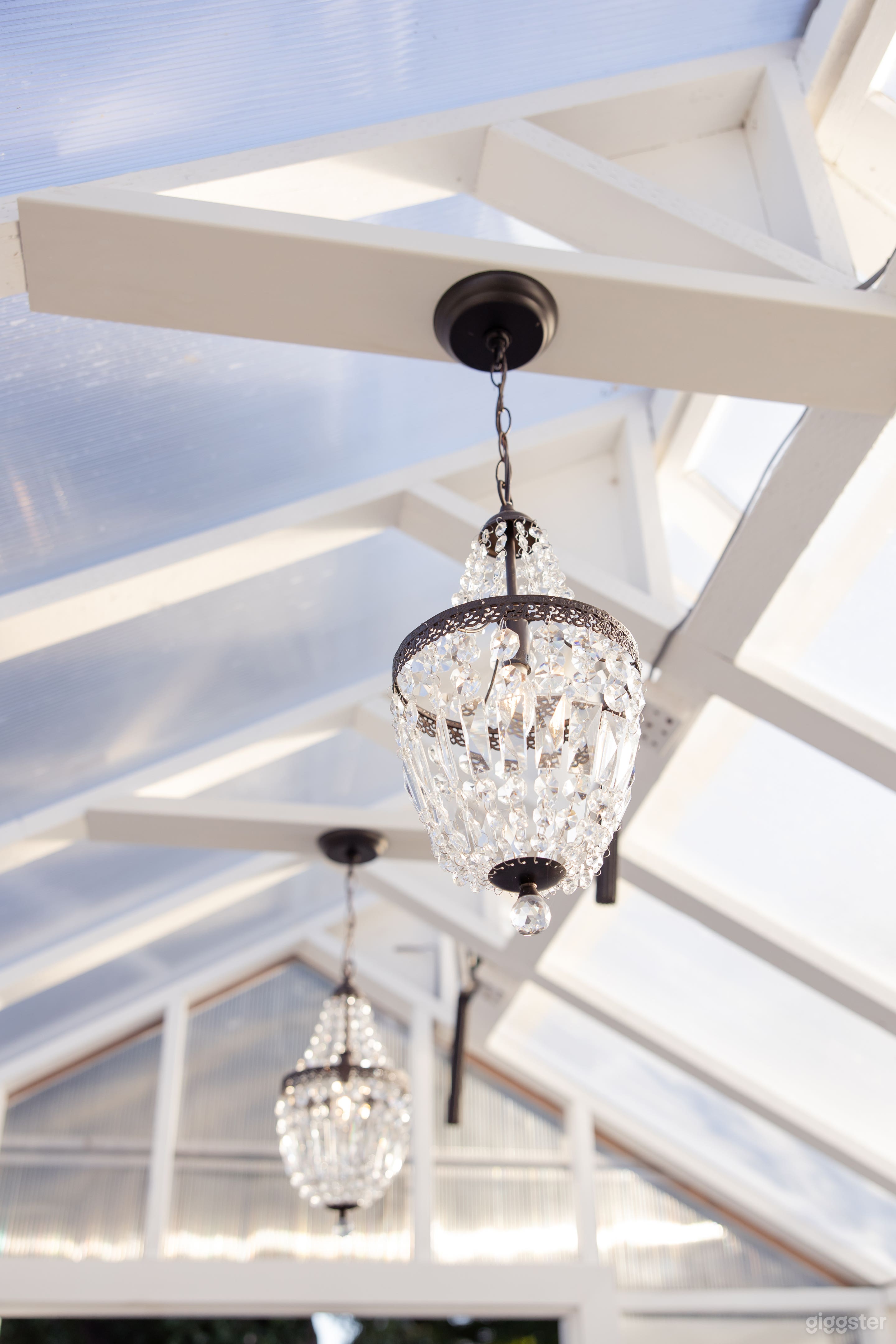 Chandeliers in greenhouse. It has unique black + white tiled floors.