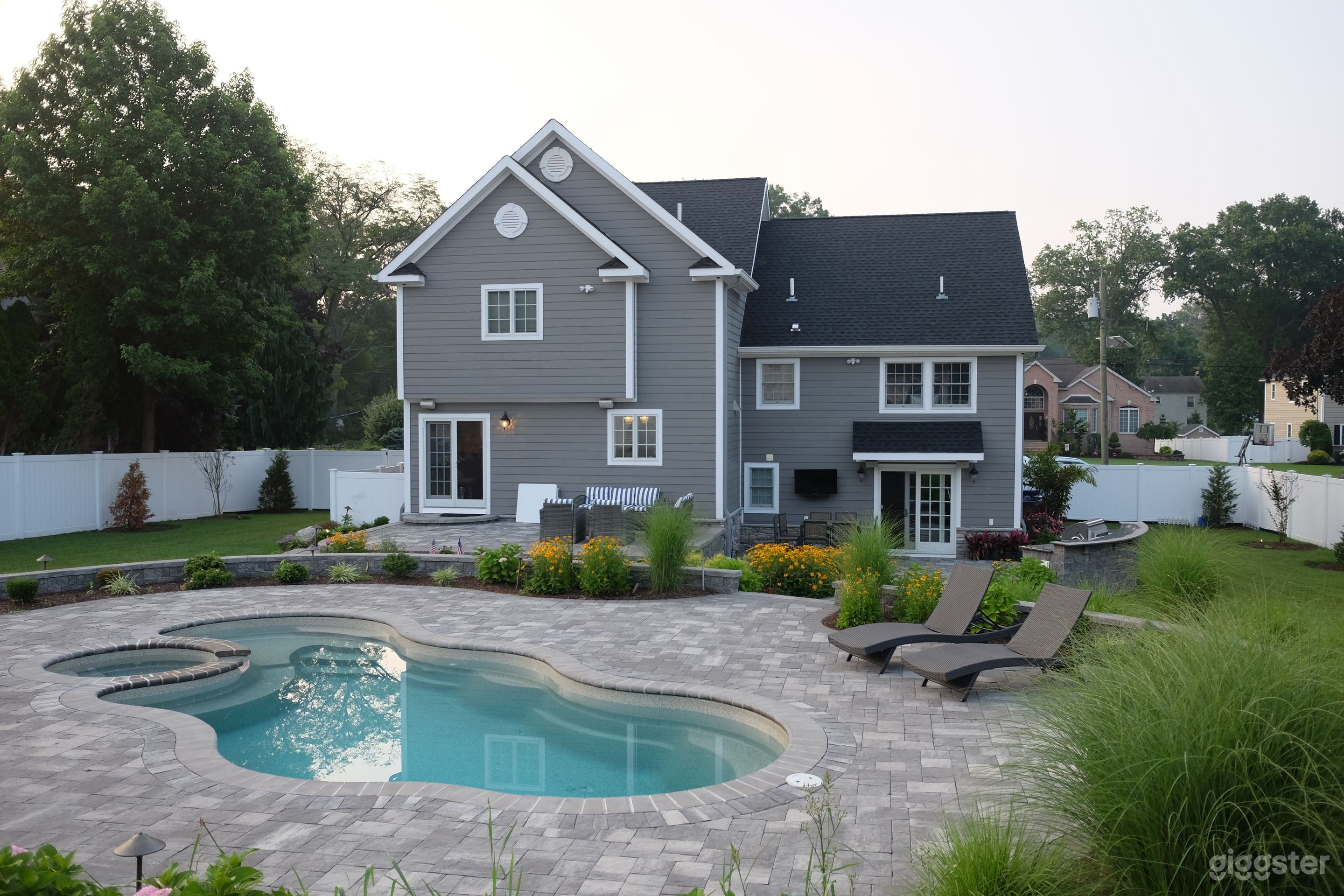 Fiberglass pool with grey stone pavers. 
