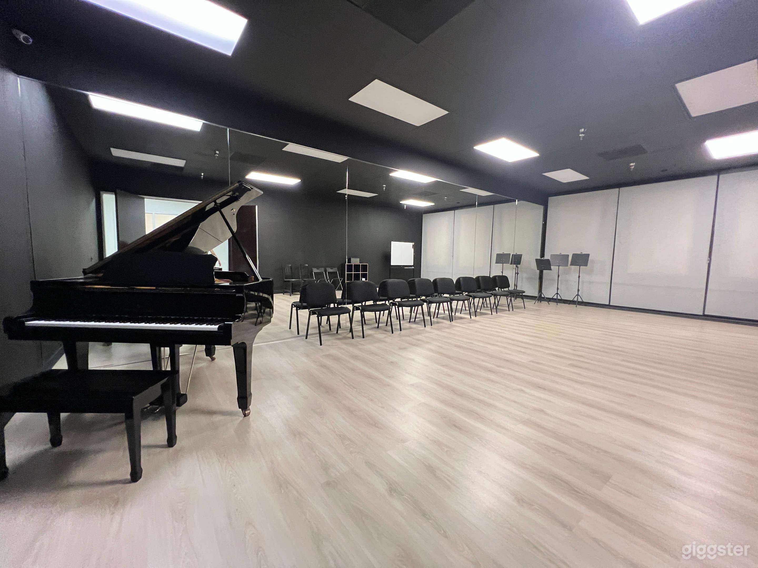 Intimate 15x25 ft blacked-out room with 8 ft mirrors, elegant piano, and built-in speakers—perfect for refined dance, piano / concert rehearsals.