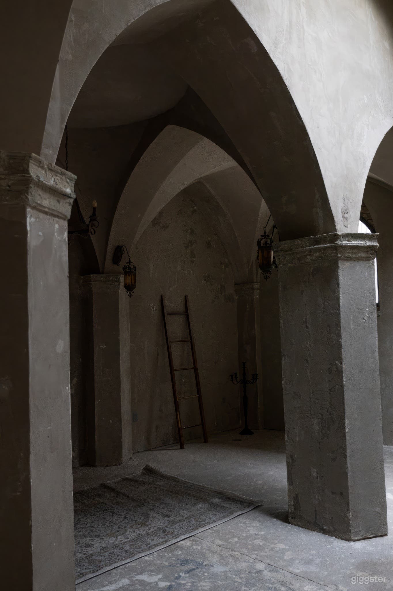 Studio room with medieval elegance featuring arched pillars and gray plastered walls, evoking authentic old-world ambiance