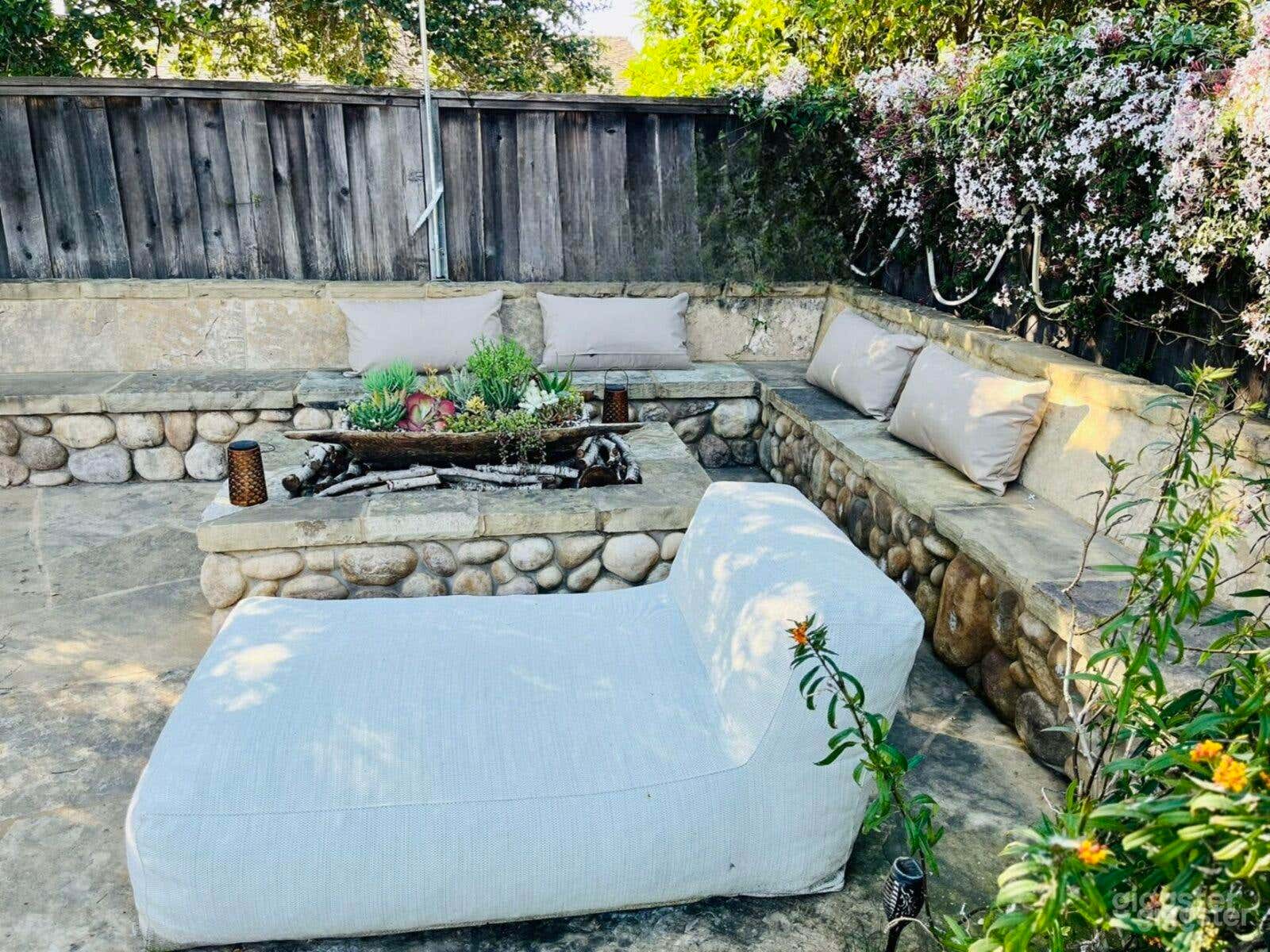 Outdoor stone wood-burning firepit set up as meditation or conversational nook. Perfect for interview-style filming, golden hour shots, intimate gatherings, wellness and lifestyle shots