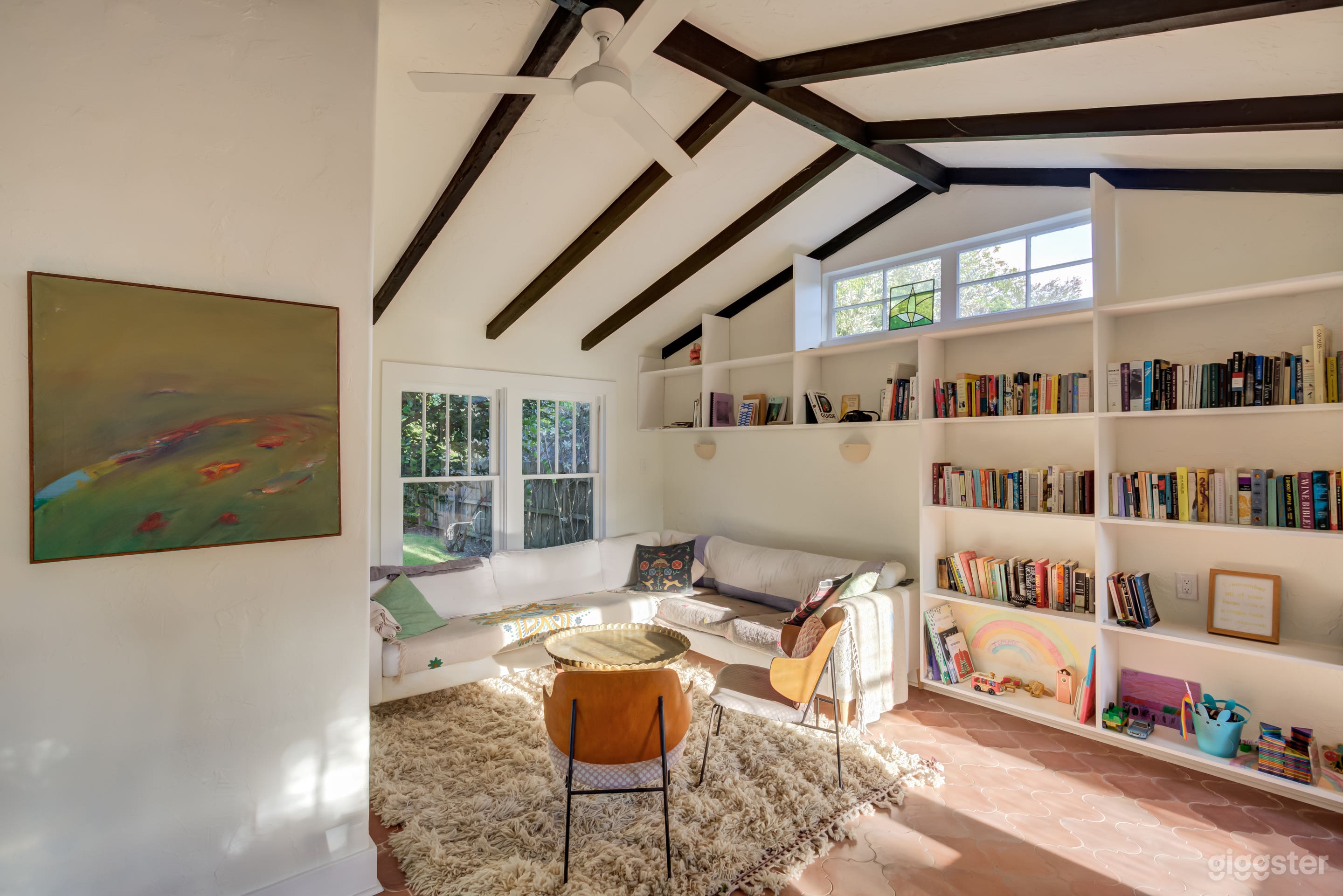 Living/dining room in main home boasts vaulted ceilings, exposed wood beams, encaustic Cuban tile, built-in bookshelves and east/west facing windows that allow plenty of rich light in throughout the day. 