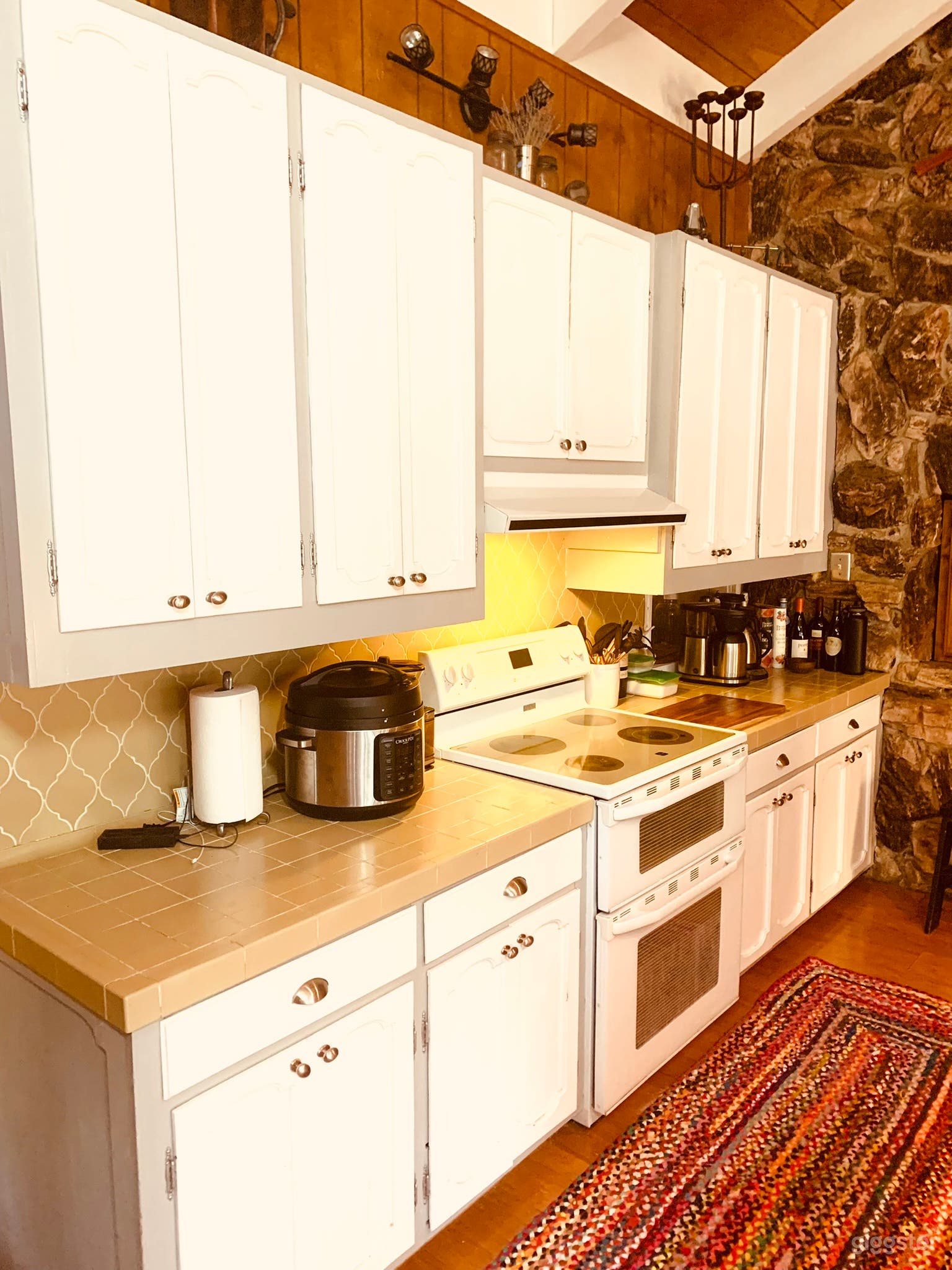 Retro open kitchen with a beautiful stone wall in the back.