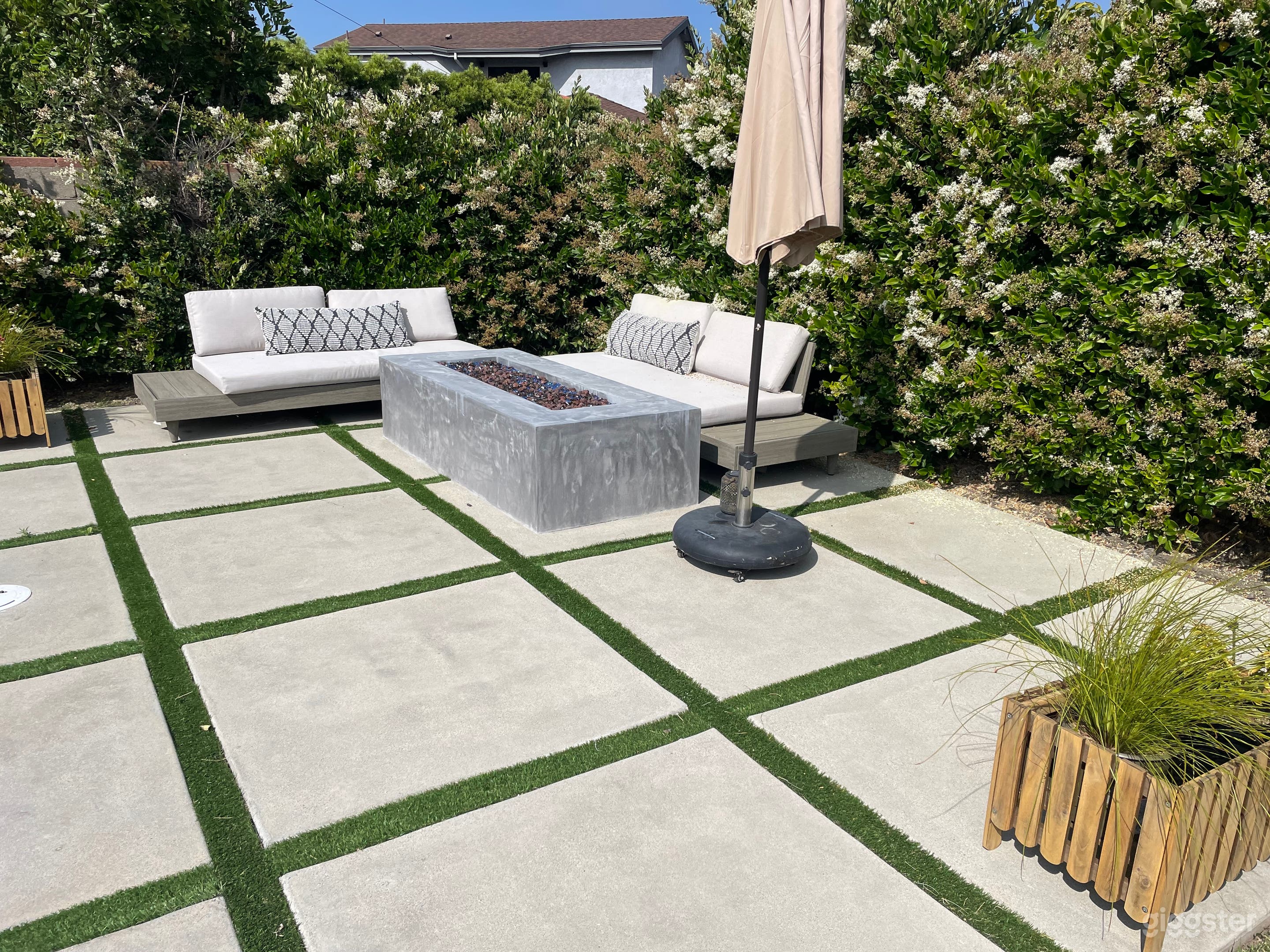 Firepit surrounded loungers and umbrella parallel to the pool.