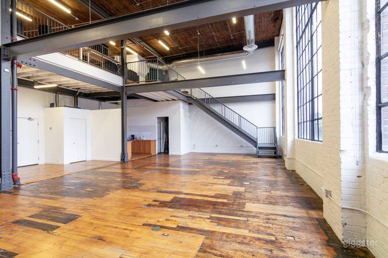  Espacio principal del estudio Lansdowne Lofts con suelos de madera auténtica y acceso por escalera al entresuelo y al patio en la azotea. 