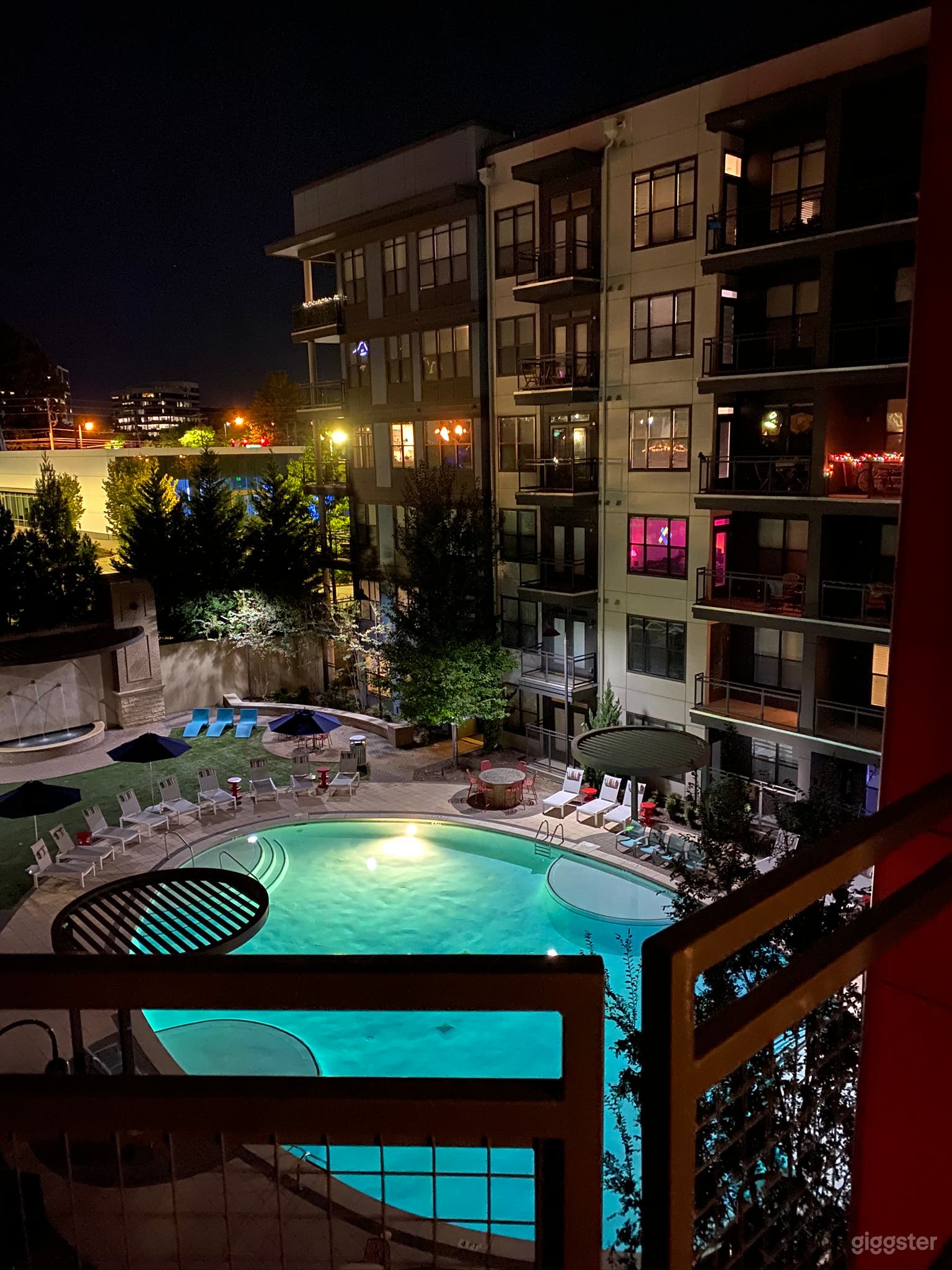 Well lit outdoor balcony view featuring pool and fountain.