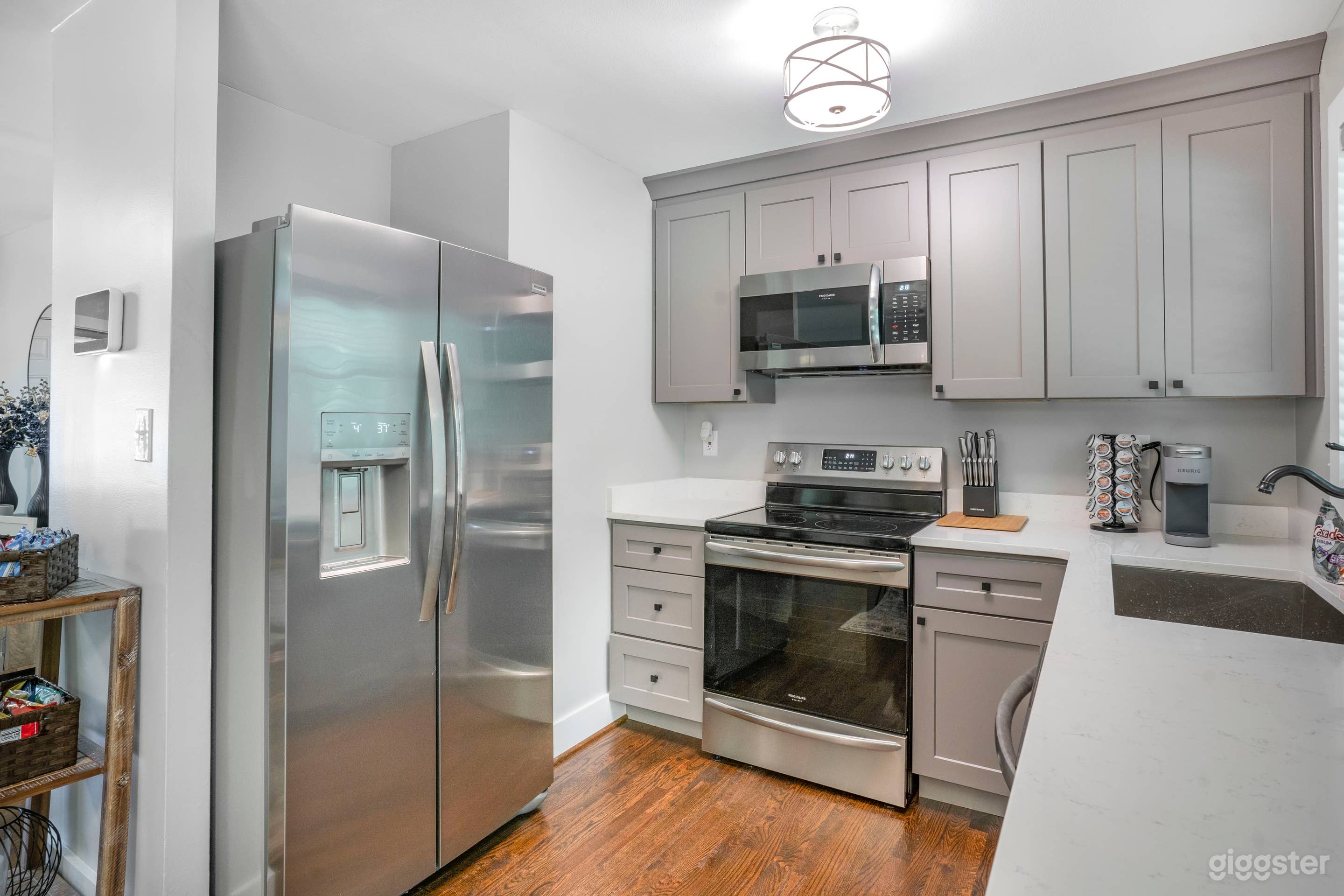 GREY TONE CABINETRY WITH HIGHEND STAINLESS STEEL APPLIANCES, QUARTZ COUNTERTOP, WITH A BLACK FARMERS WELDED SINK, KEURIG WITH COFFEE AND TEA ALONG WITH COMPLIMENTARY WATER AND JUICE 