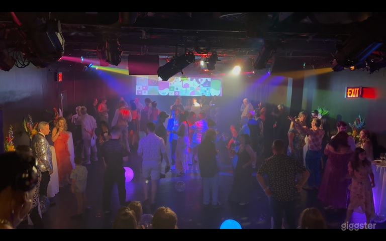  View of the theater with people on the stage for an event, with theatrical lighting. 