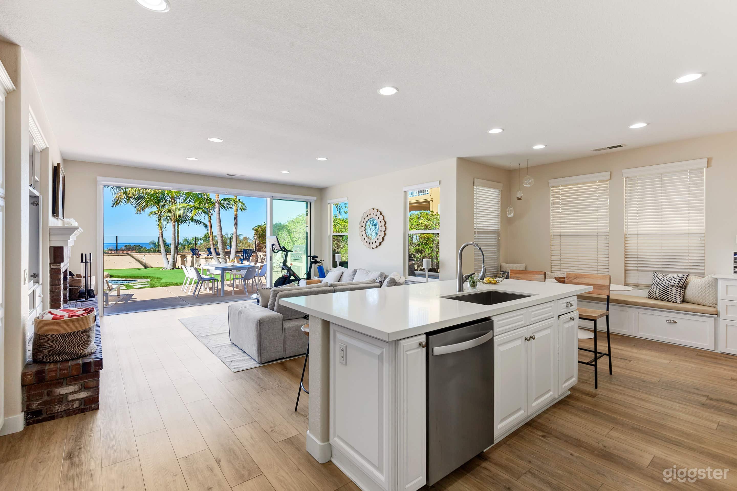 White marble kitchen counters with 13 ft glass floor to ceiling sliding doors with light hardwood floors creates indoor outdoor living space 