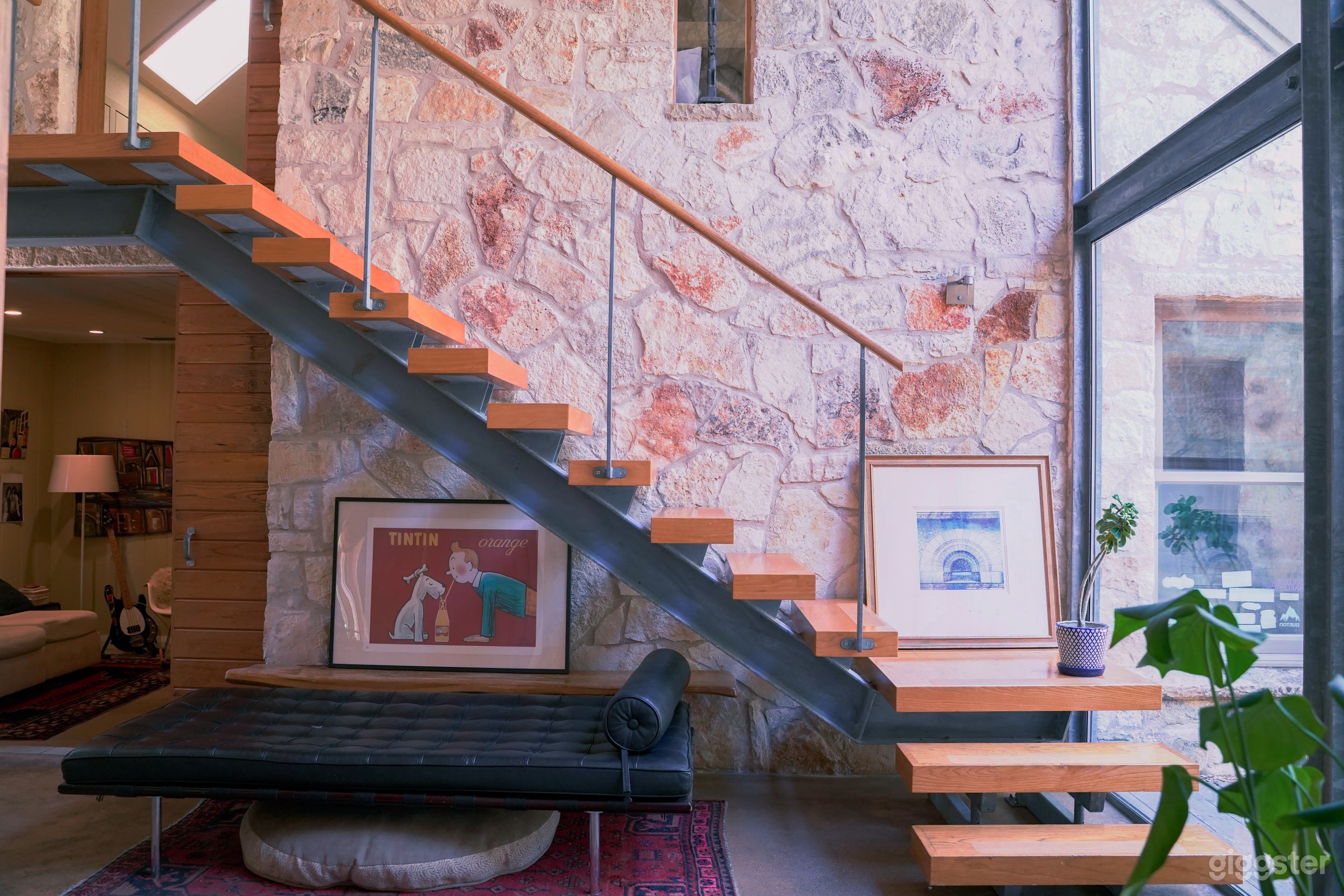 Floor to ceiling windows, stone walls, mid-century modern decor, exposed floating staircase, wood and steel