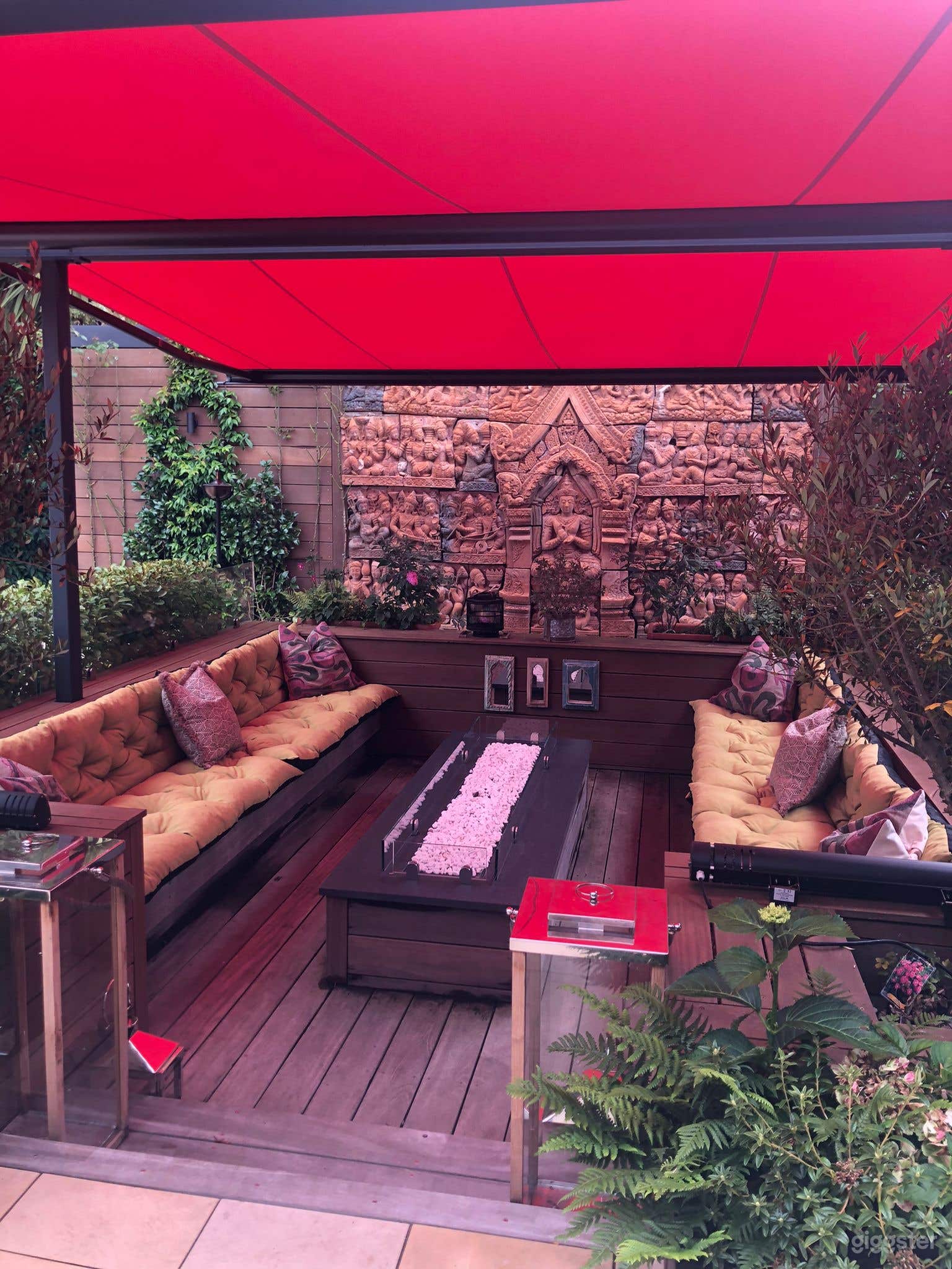 Sunken in outdoor seated area with red awning and a Thai wall backdrop