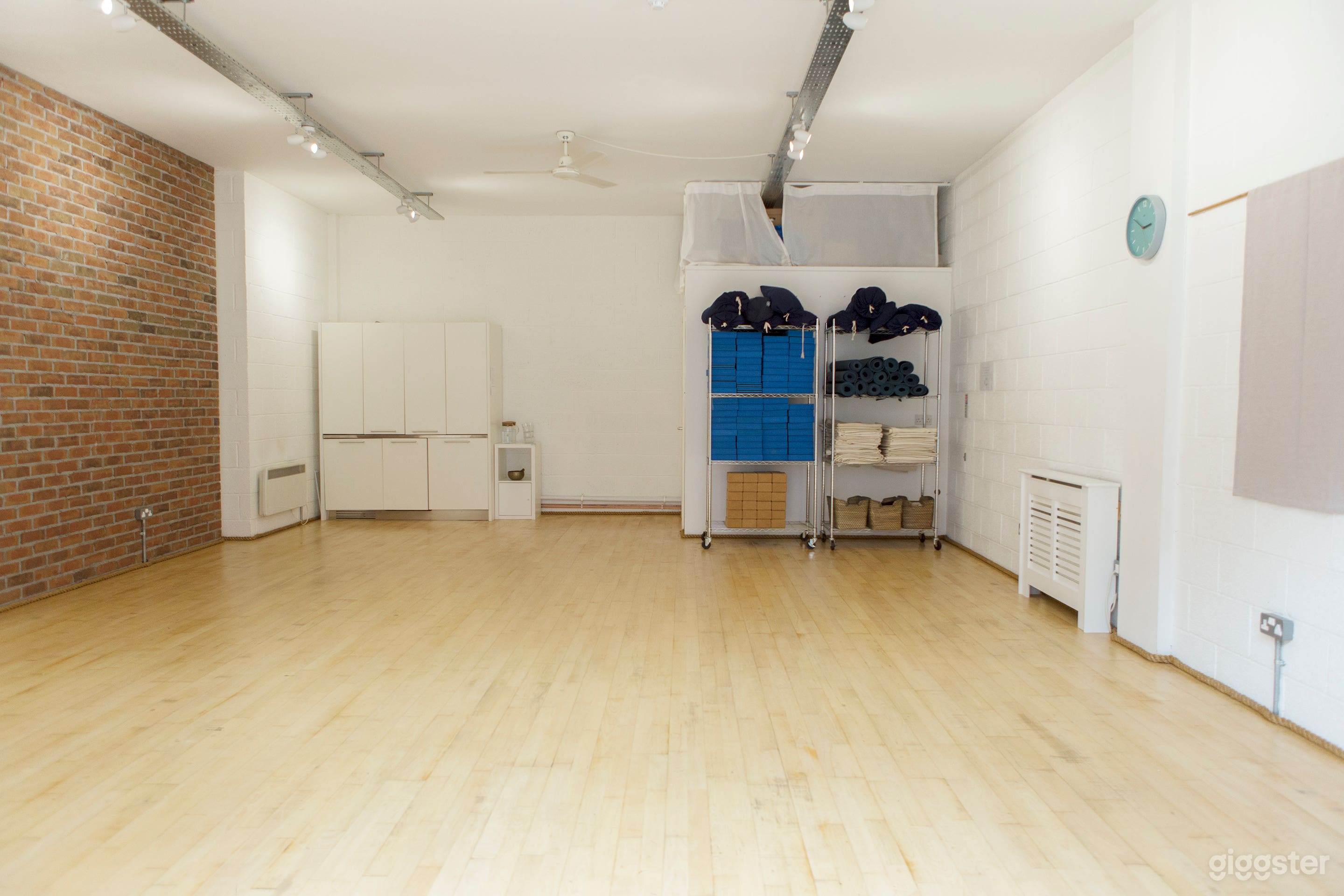 The studio view from the entrance showing kitchenette (left) and toilet cubicle (behind yoga equipment)