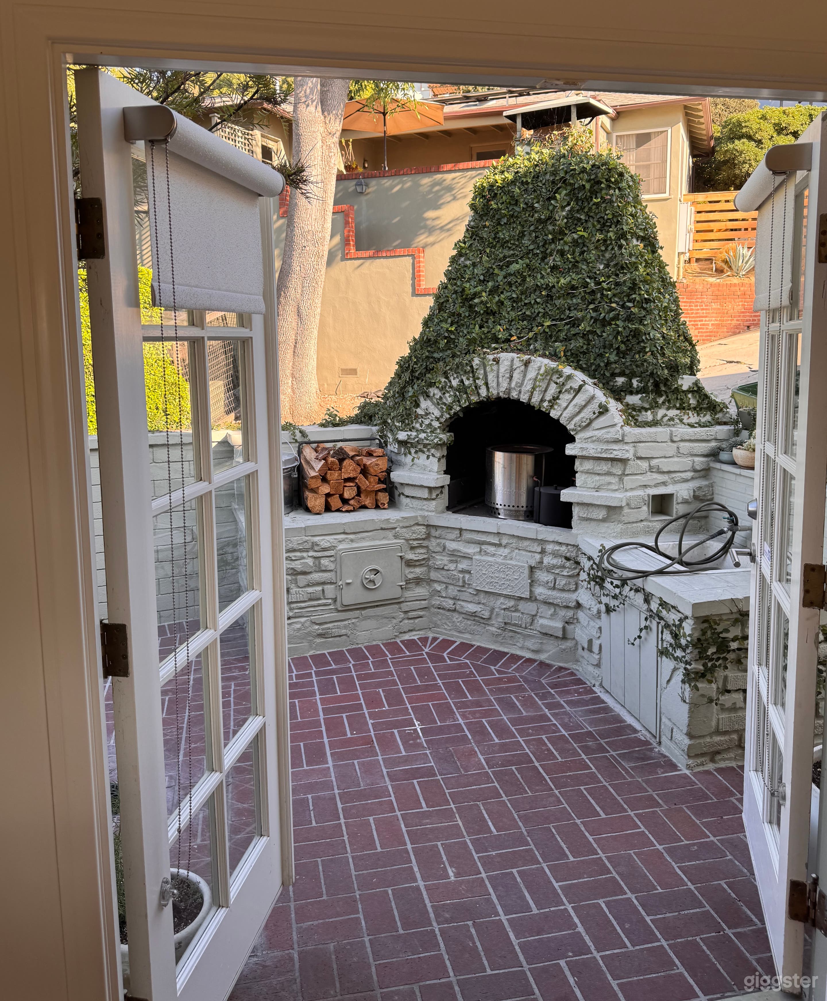 Charming brick patio with outdoor fireplace and ivy backdrop, ideal for outdoor dinners, interviews, or European-inspired lifestyle shoots.