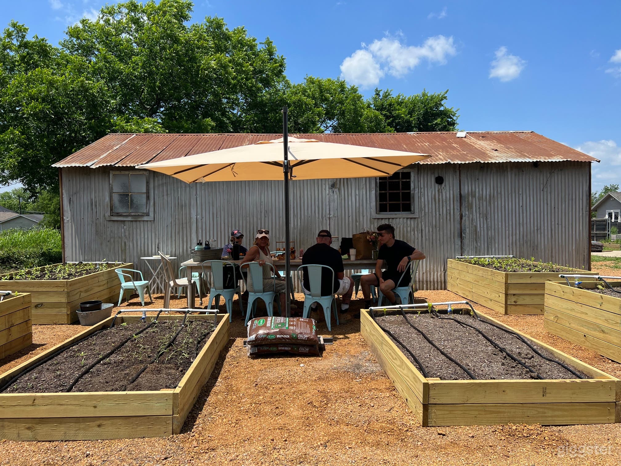 Farm table with blue chairs, will soon have a pergola that will replace the umbrella 