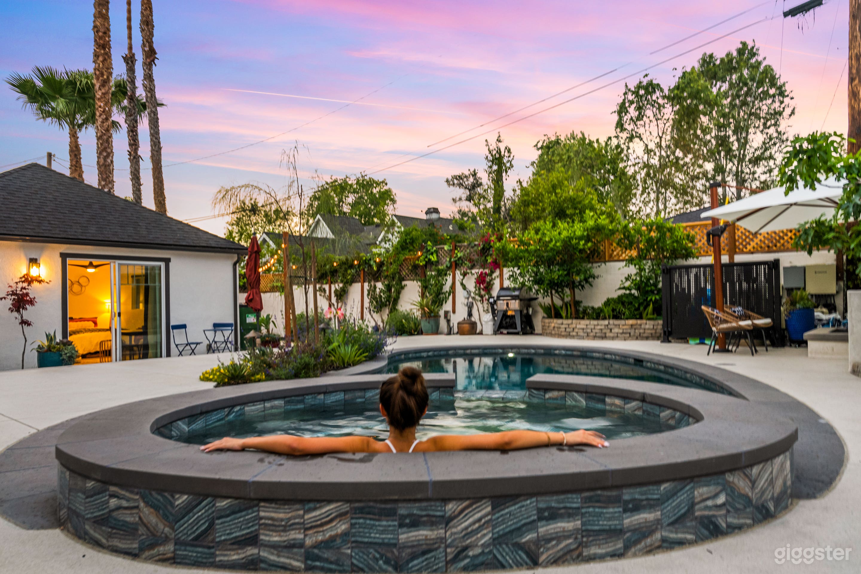 Our serene backyard oasis features a heated spa, sparkling pool, and lush greenery—framed by cotton candy skies at golden hour. Whether you're capturing relaxed luxury, lifestyle content, or summer vibes, this space delivers cinematic charm with every shot