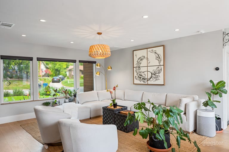  Framed by large windows, the spacious living area invites warm sunlight and views of the lush garden outside. With the comfy L-shaped sofa and rustic accents inside, it’s a serene spot where indoor comfort meets nature’s calm — perfect for relaxed scenes 