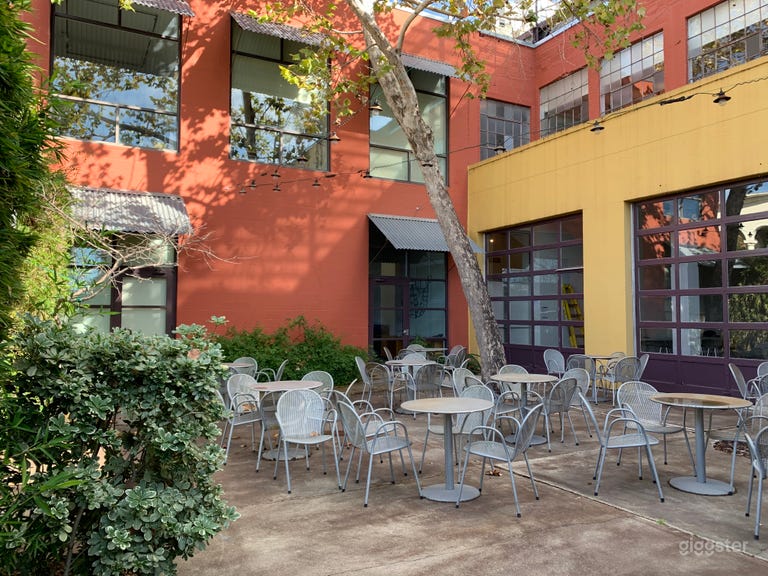  The Courtyard with outdoor tables and chairs surrounded by plants and colorful walls. 