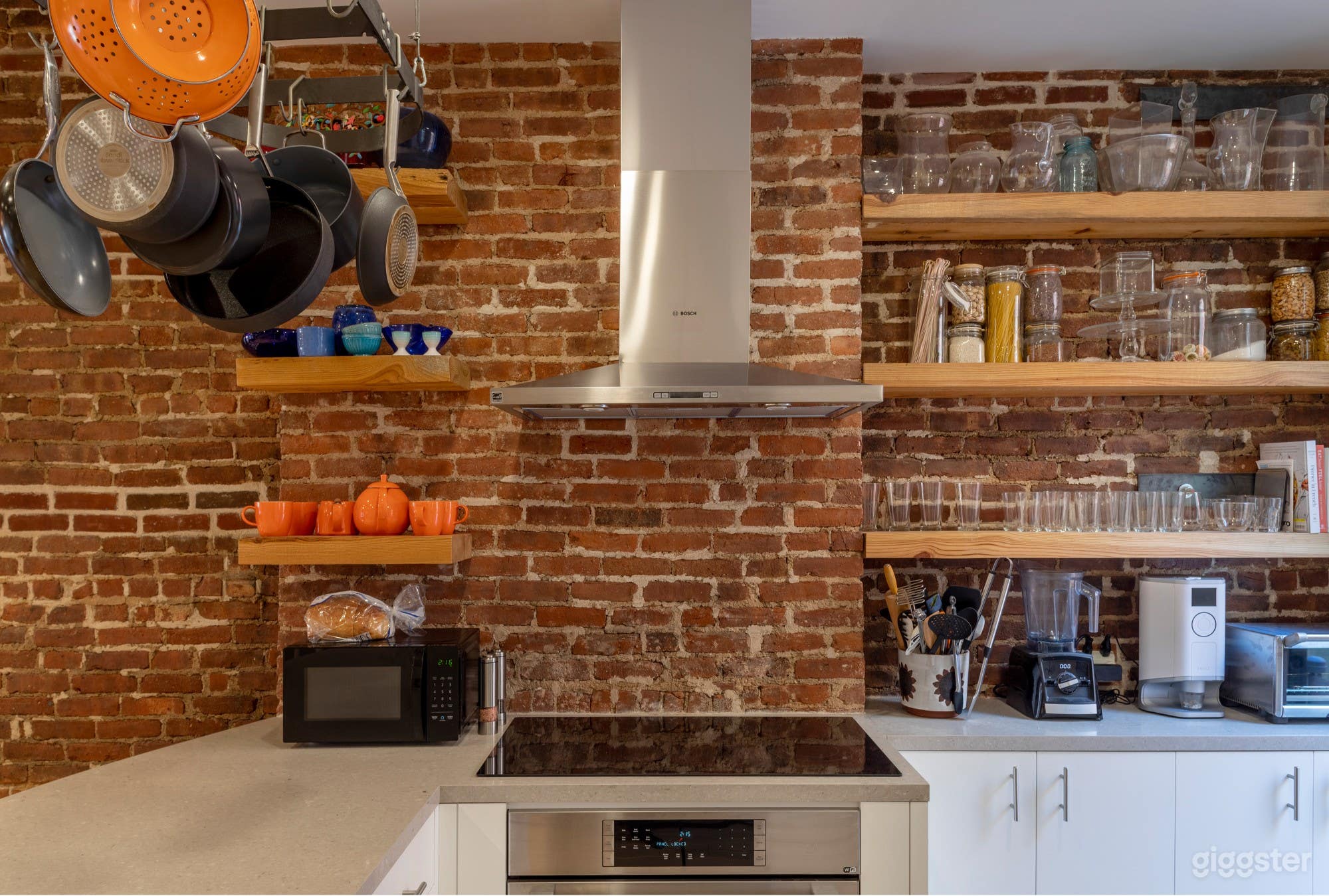 Kitchen with exposed brick, reclaimed wood shelves, natural light