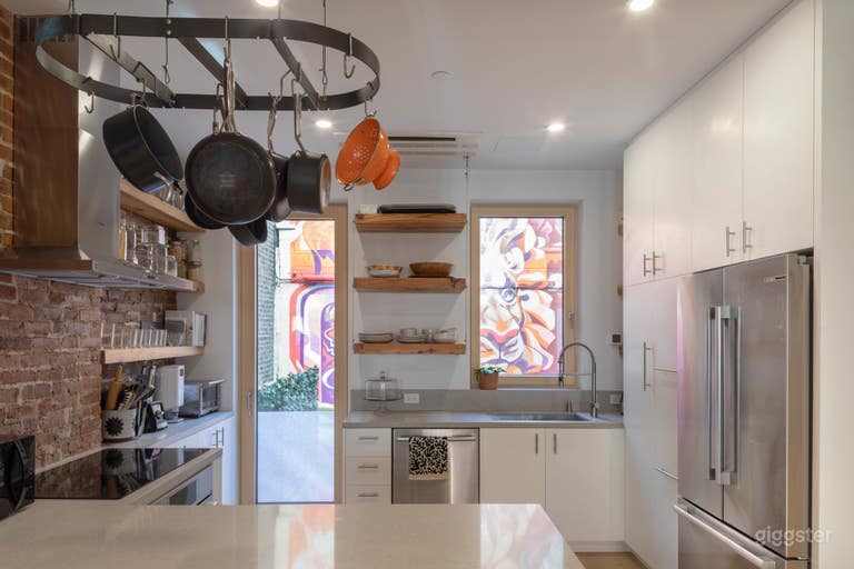  Kitchen with hanging pots and view out back windows of mural on back patio wall 