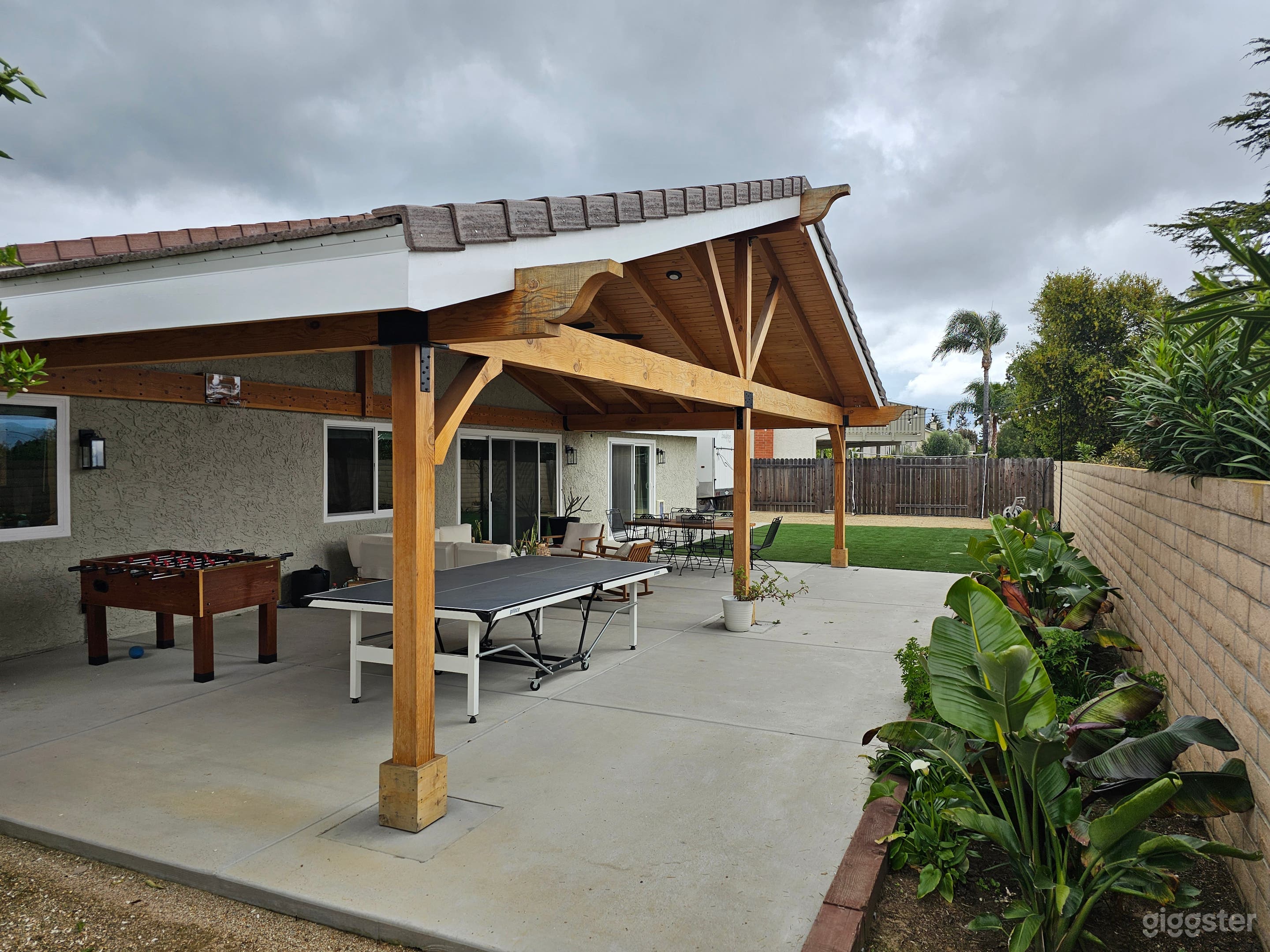 Back yard with large wooden gabled patio cover. 