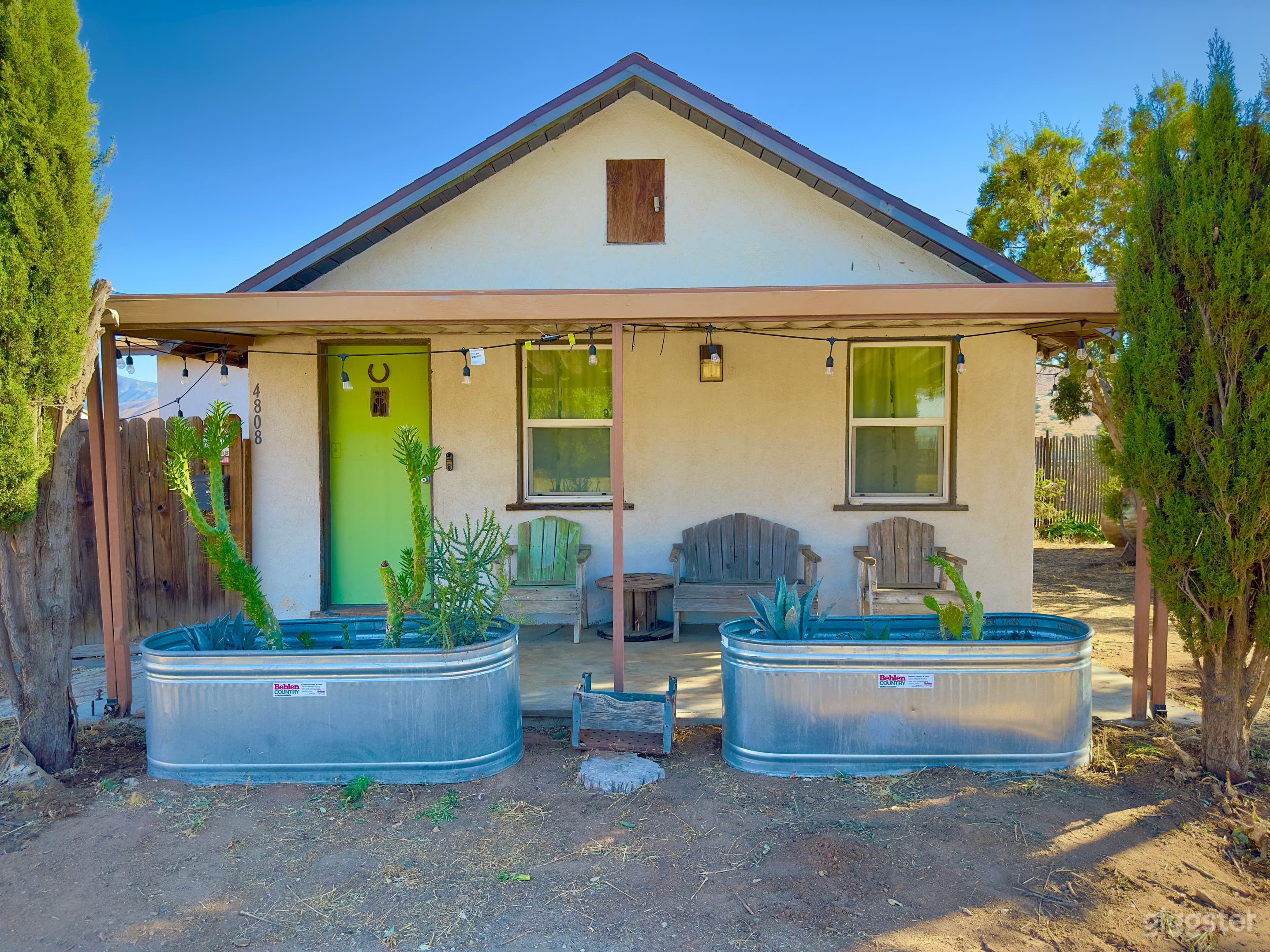 1941 stucco house with stage coach in the desert on a rustic industrial property. 