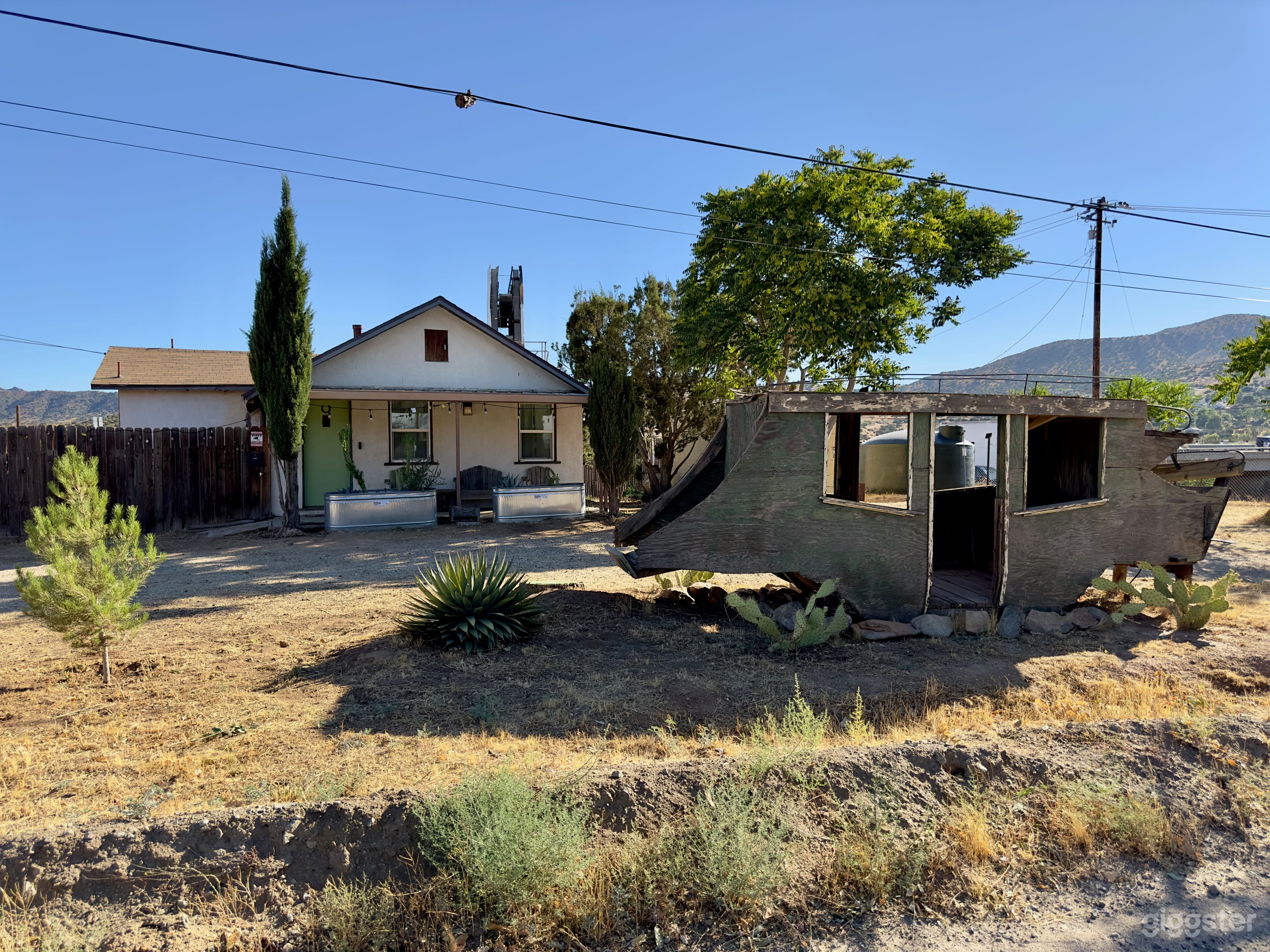 1941 stucco house with stage coach in the desert on a rustic industrial property. 