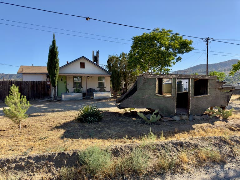  1941 stucco house with stage coach in the desert on a rustic industrial property.  
