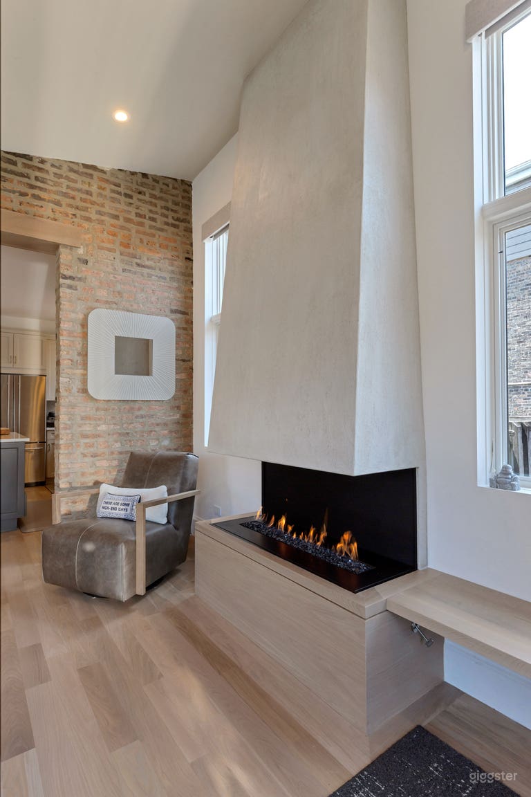  Exposed brick family room with three sided fireplace, custom built in cabinet, window surround, and 11’ ceilings 