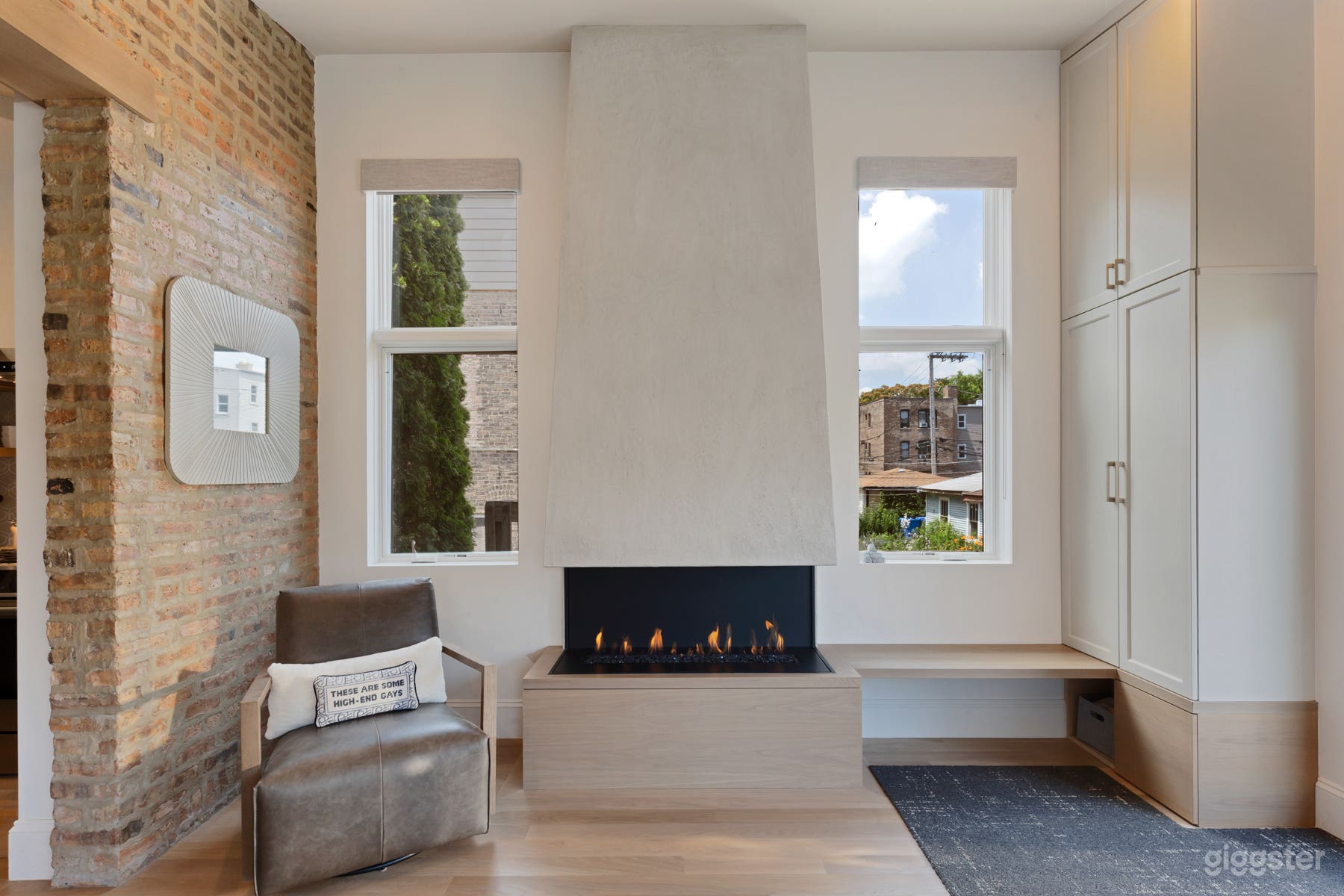Exposed brick family room with three sided fireplace, custom built in cabinet, window surround, and 11’ ceilings