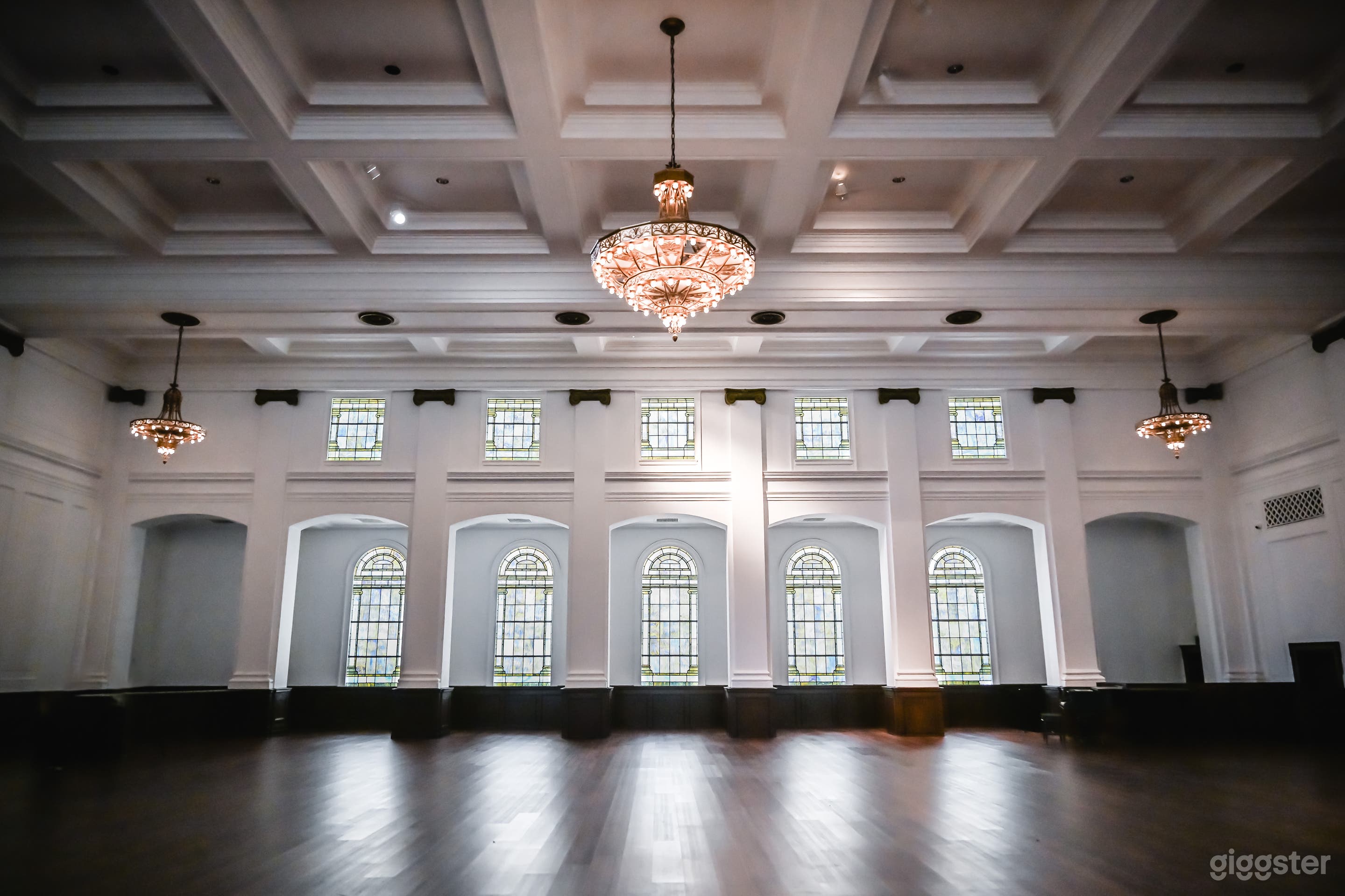 Sanctuary with large stained glass windows and vintage chandeliers
