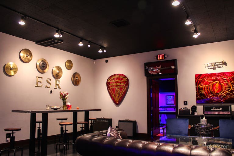  Right side Break room and lounge area has a couch with a glass guitar coffee table, 2 arm chairs, a conference or dining table with 6 adjustable stools, a kitchenette and music themed art. 