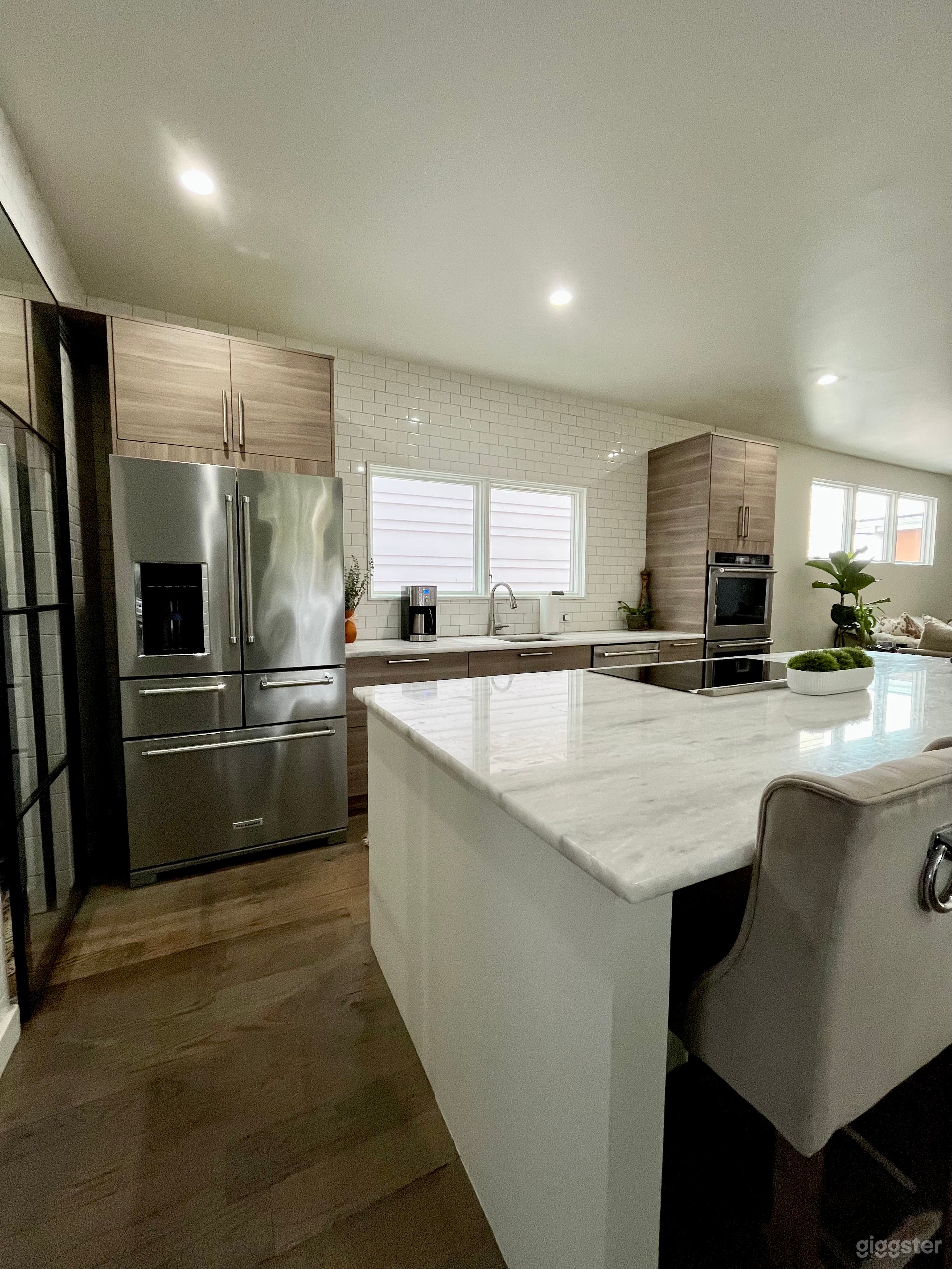Well lit open kitchen with a huge center island. White subway tile walls floor to ceiling.