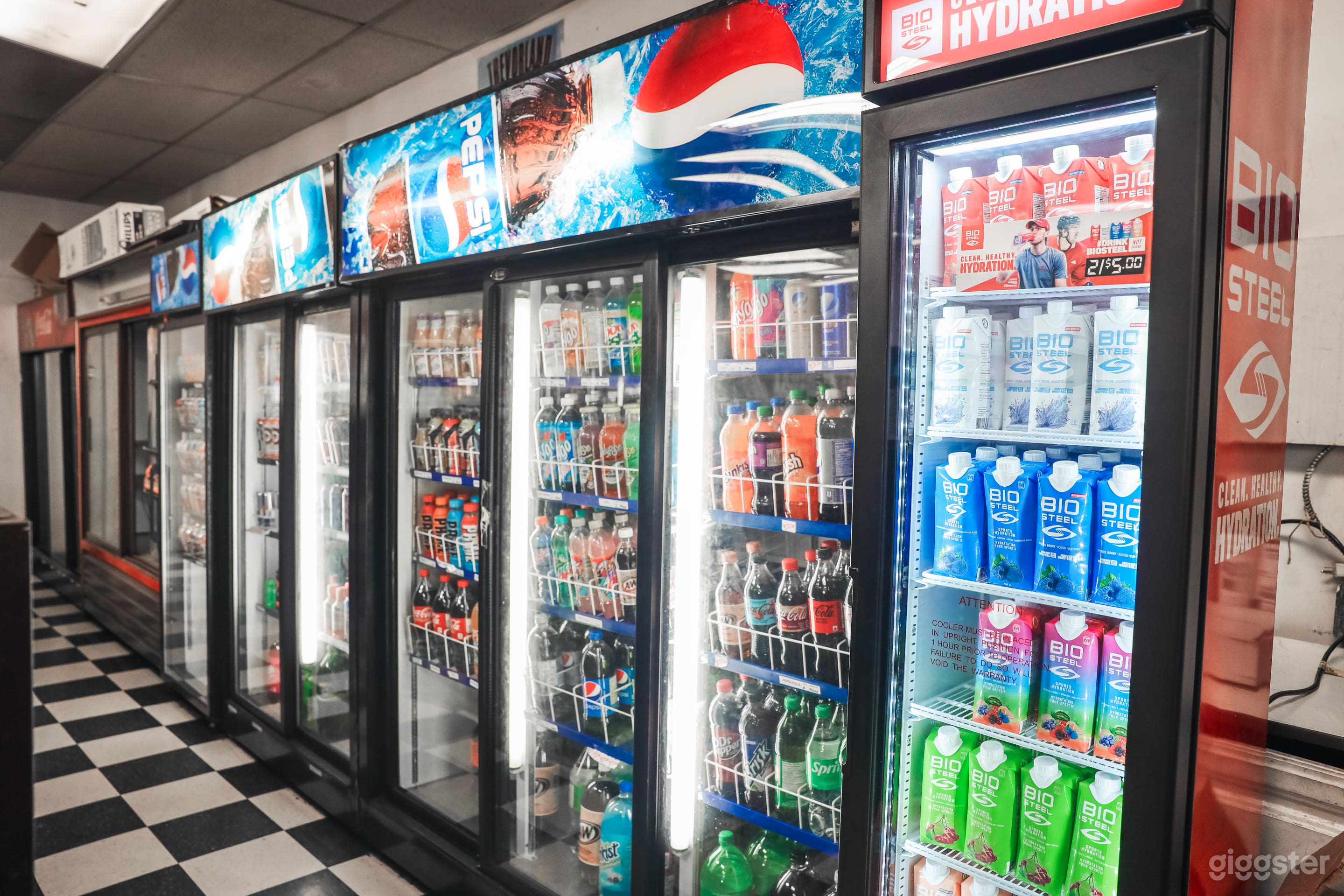 Refrigerators down one aisle with cold beverages and white lighting.