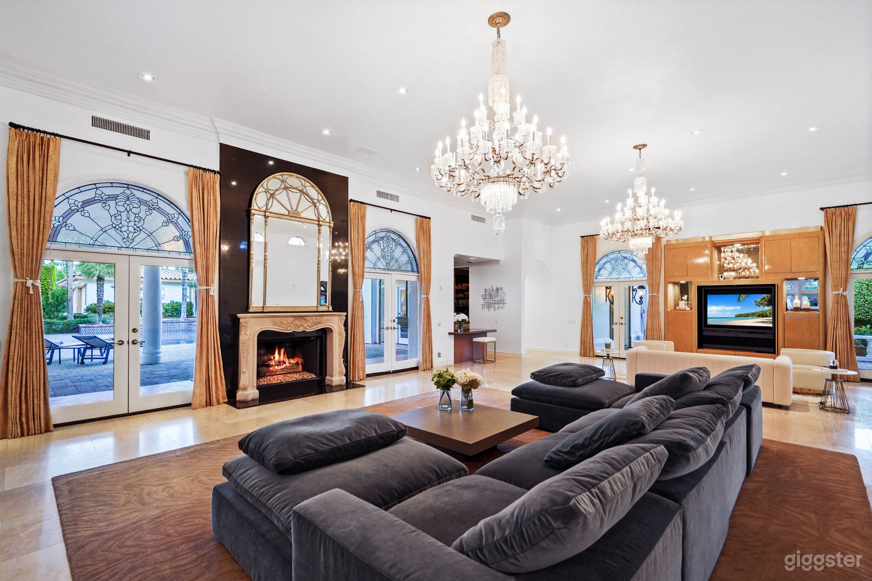 marble floored living room with fireplace and sunken bar. leads out to the pool area