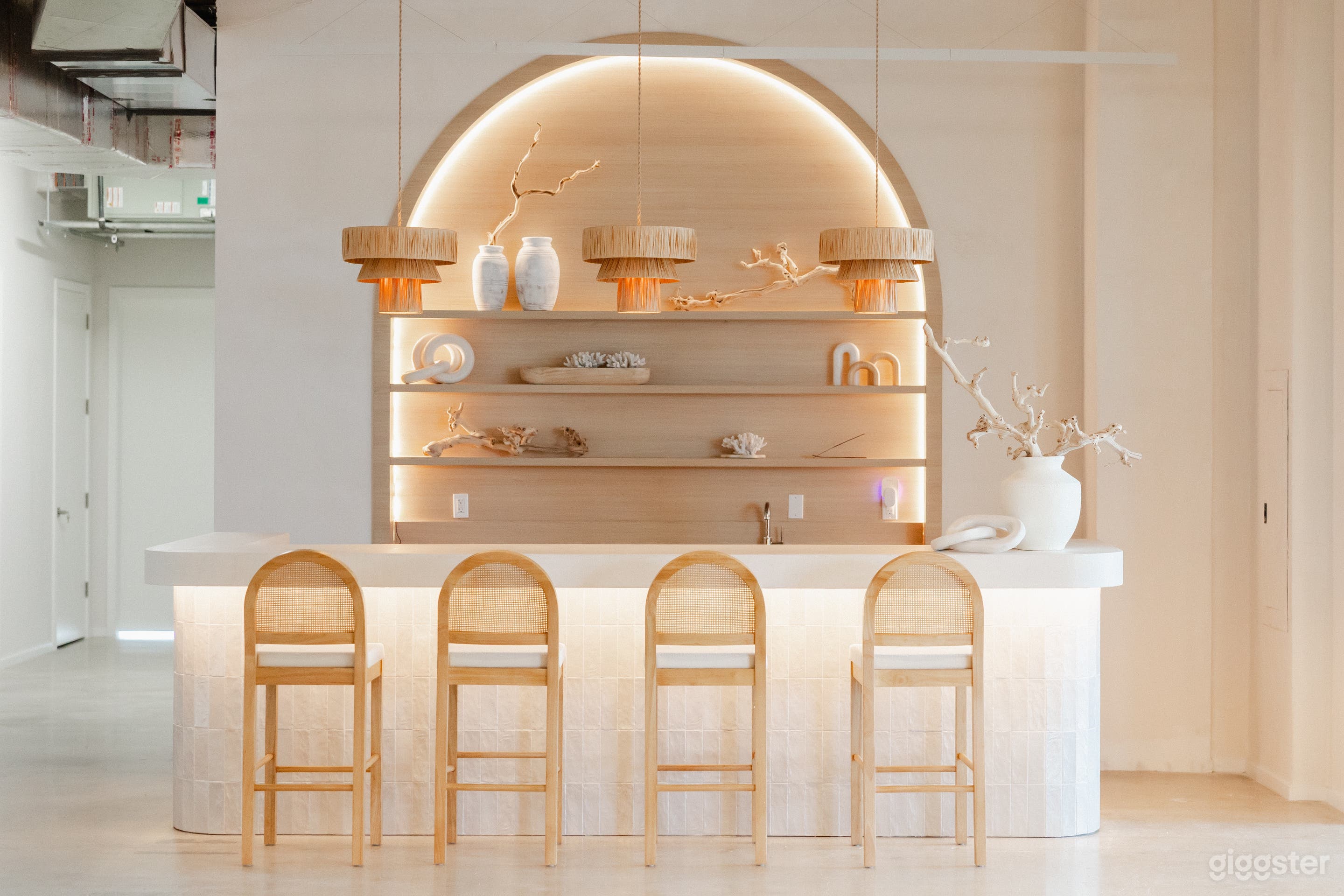 Open Bar Design: A modern bar with a large arched shelving unit and LED lights, perfect for displaying products or serving drinks. The oversized kitchen island is fully equipped with a sink, fridge, dishwasher, and microwave, making it ideal for catering.