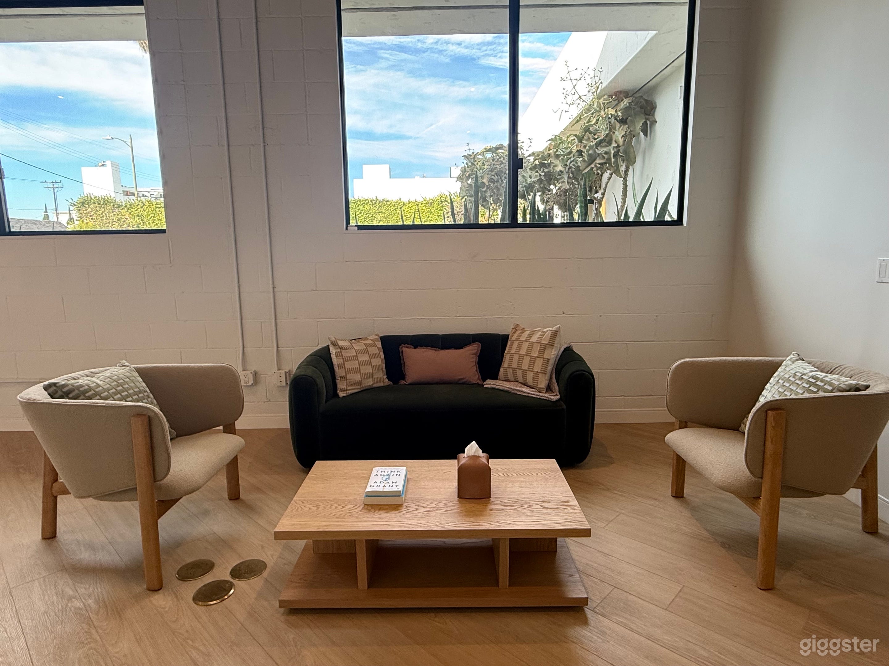 Bright lounge/waiting area with natural light, modern seating, and a coffee table.
