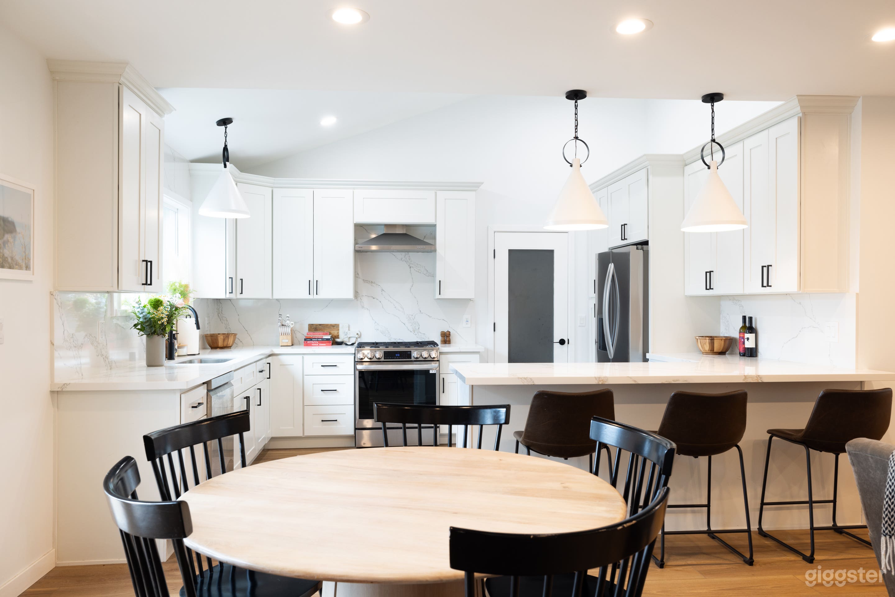 Open concept kitchen, bar with barstools, dining room with round table