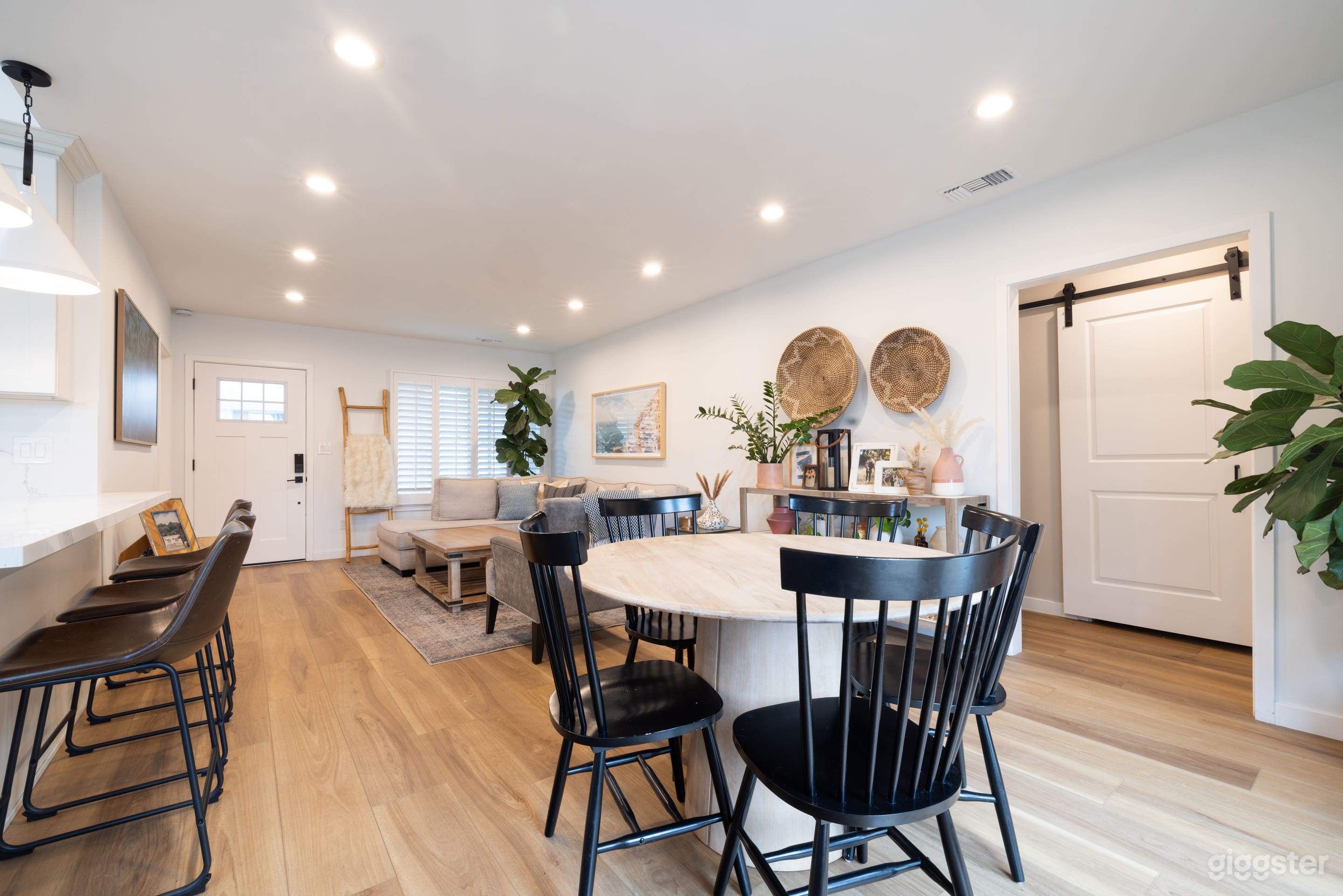 Dining room area with round whitewashed wood table and black chairs